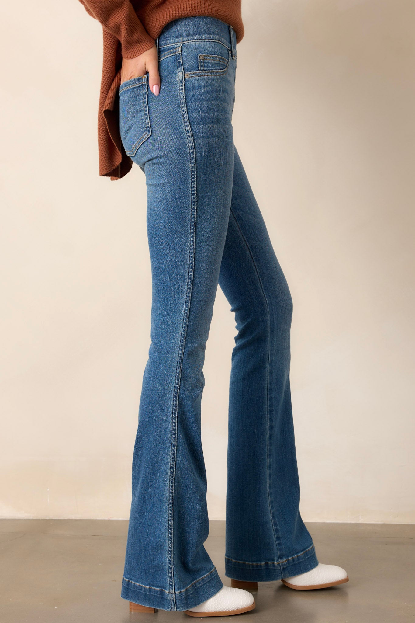 Side view of these jeans that feature a high waist, functional belt loops, slip on design, and a flared leg.