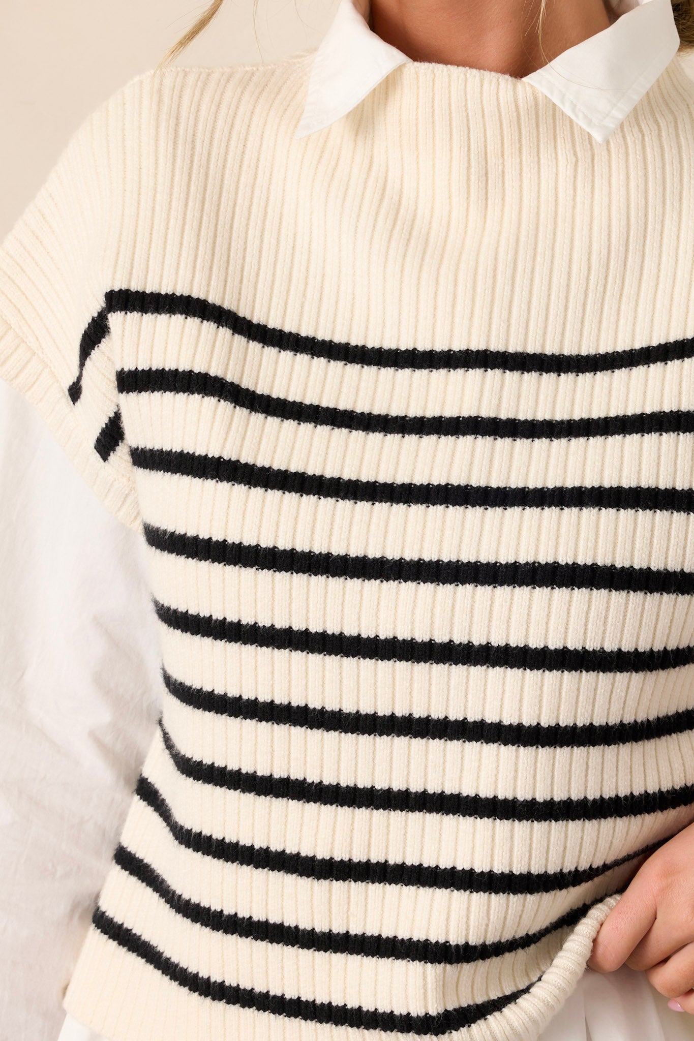 Close-up of the ivory stripe top focusing on the high neckline, black horizontal stripe pattern, and the texture of the thick knit material.