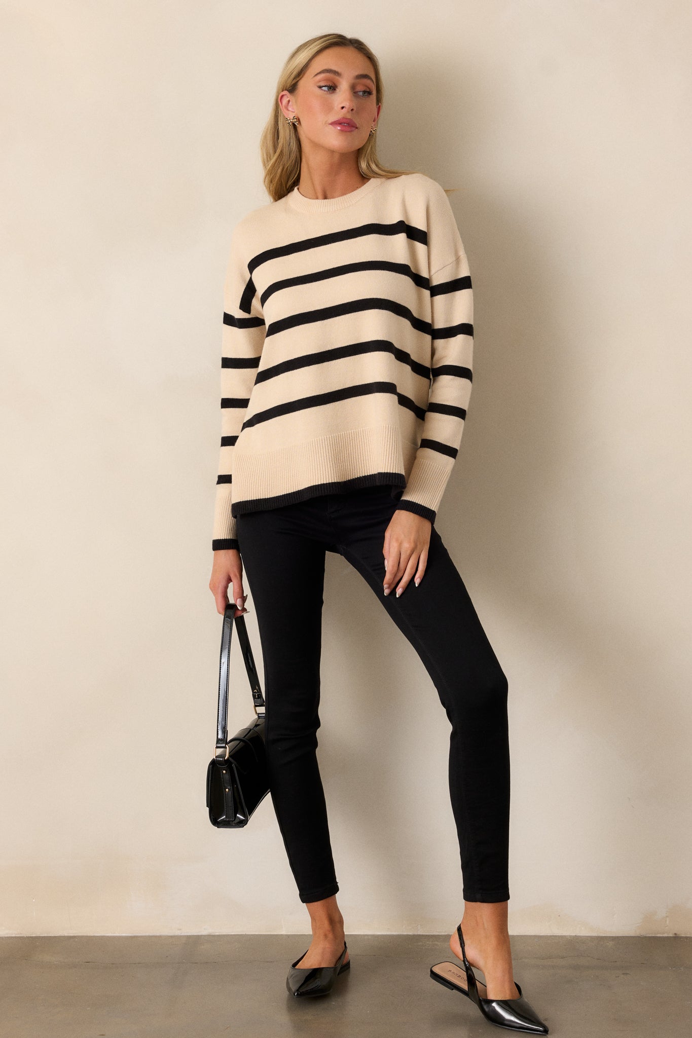 Full-length view of the beige sweater showcasing its ribbed crew neckline, long sleeves, and horizontal stripe pattern.