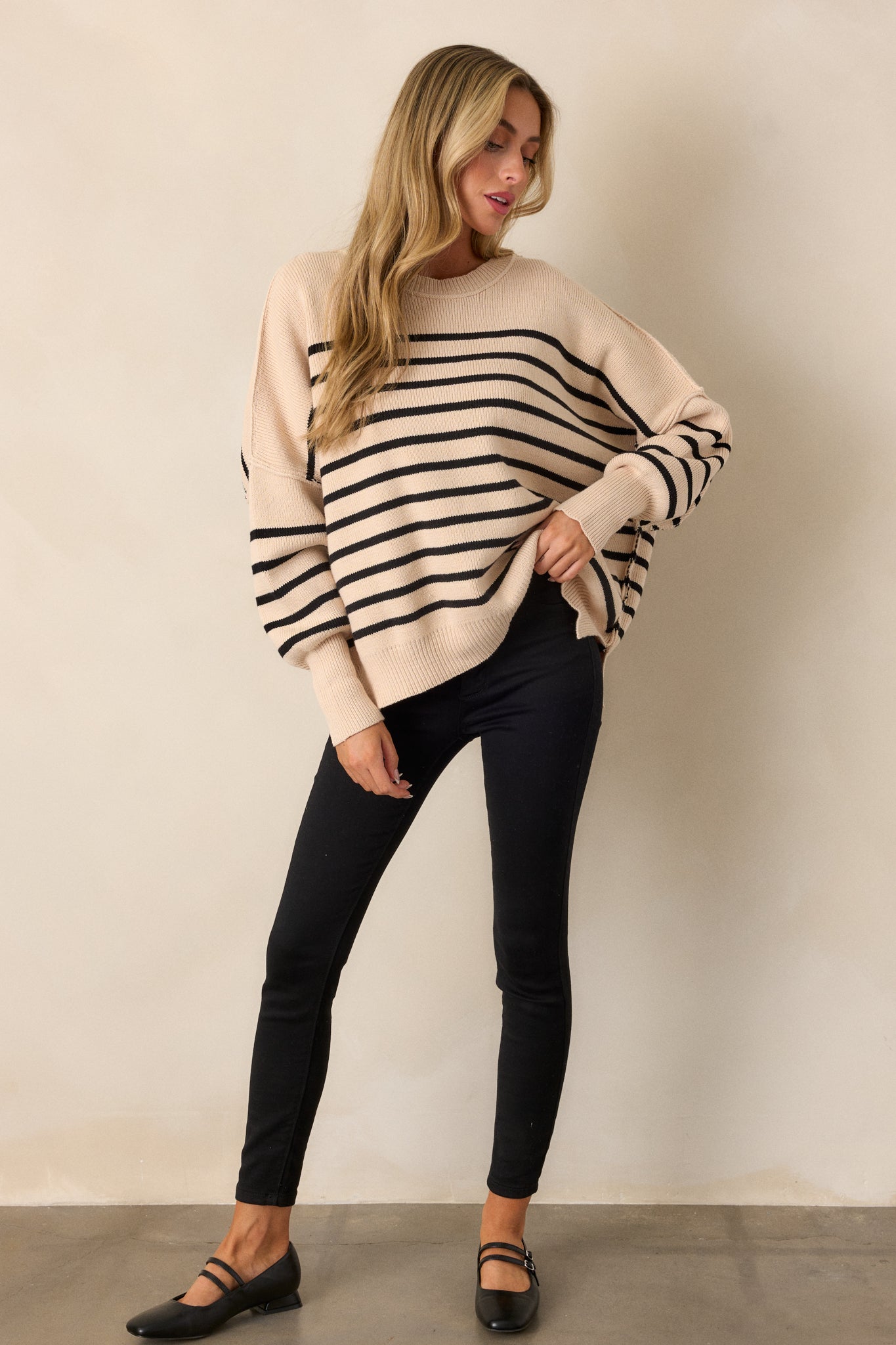 Full-length shot focusing on the beige sweater’s horizontal stripe pattern and its loose, comfortable fit.