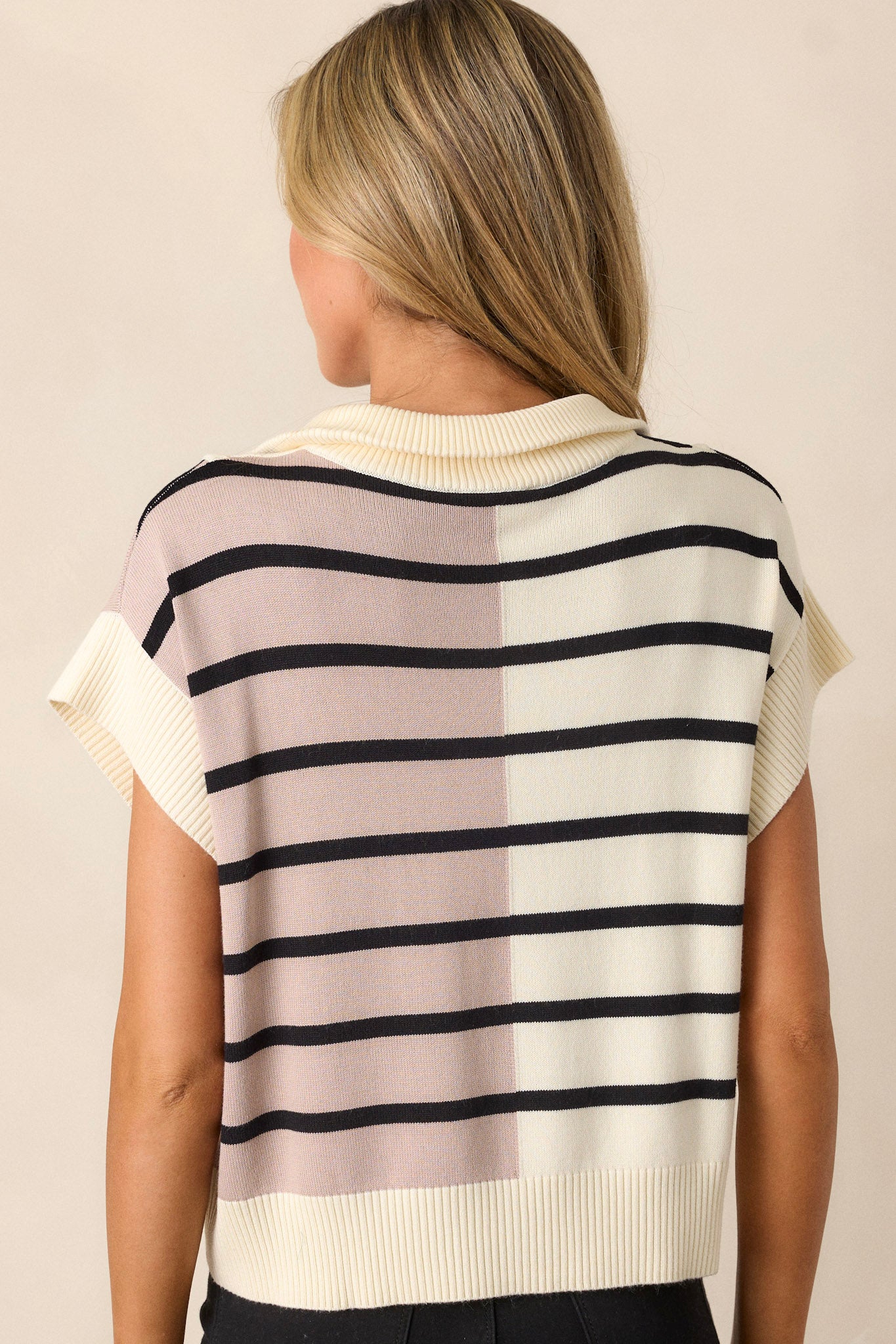 Back view of a beige sweater highlighting the bold striped design and ribbed cap sleeves.