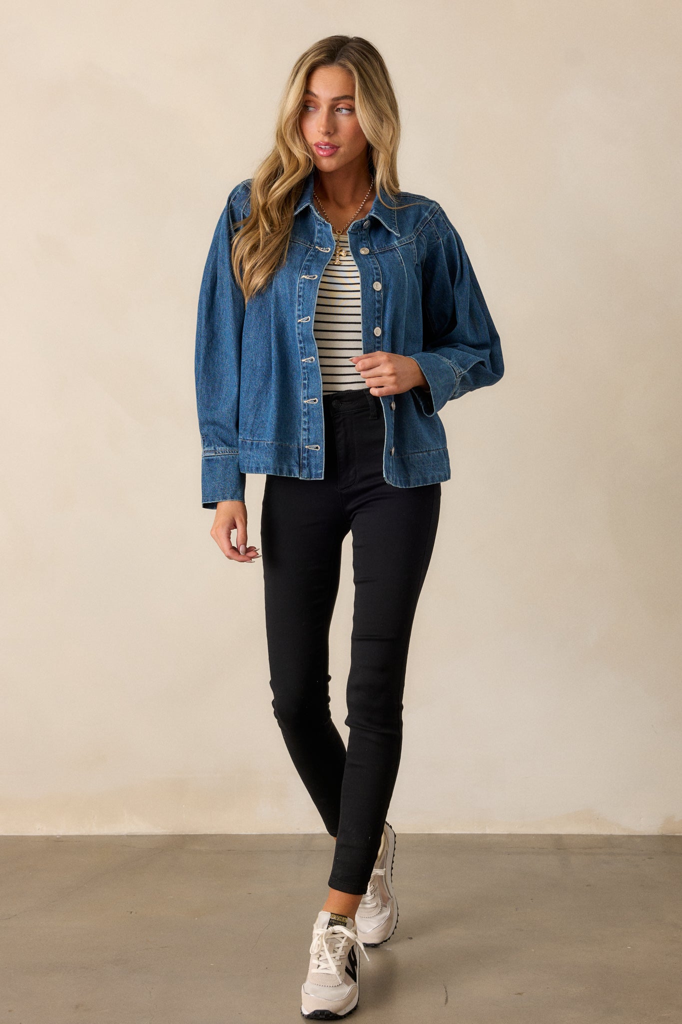 Full-length shot emphasizing the structured fit, collared neckline, and detailed stitching along the shoulders of the dark wash denim jacket.