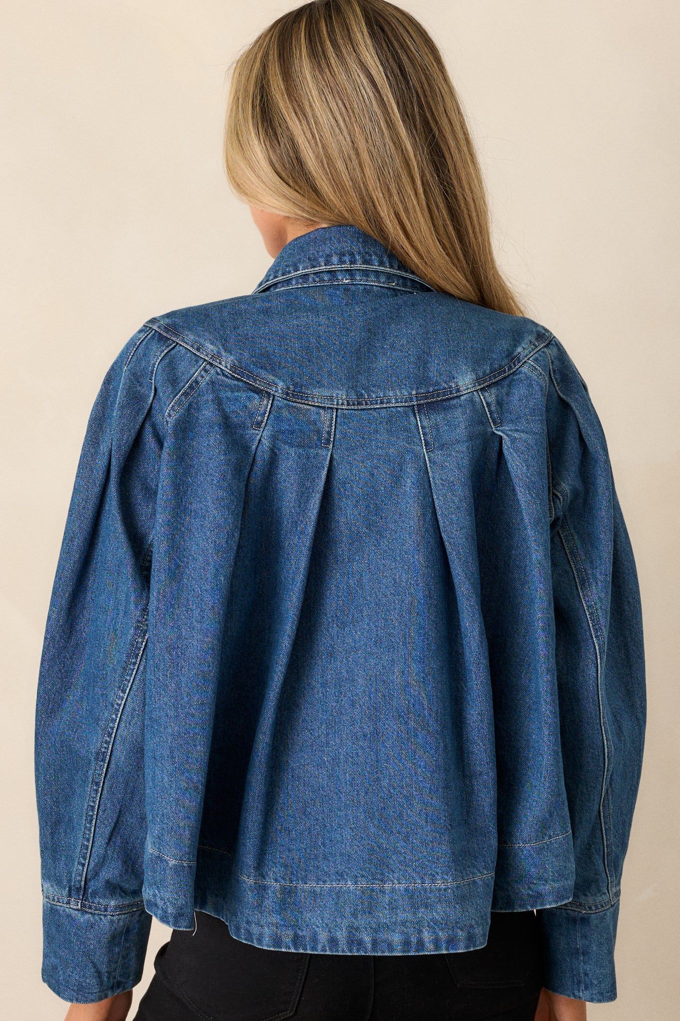 Rear view of the dark wash denim jacket, showcasing the clean lines, detailed shoulder stitching, and dark denim fabric.