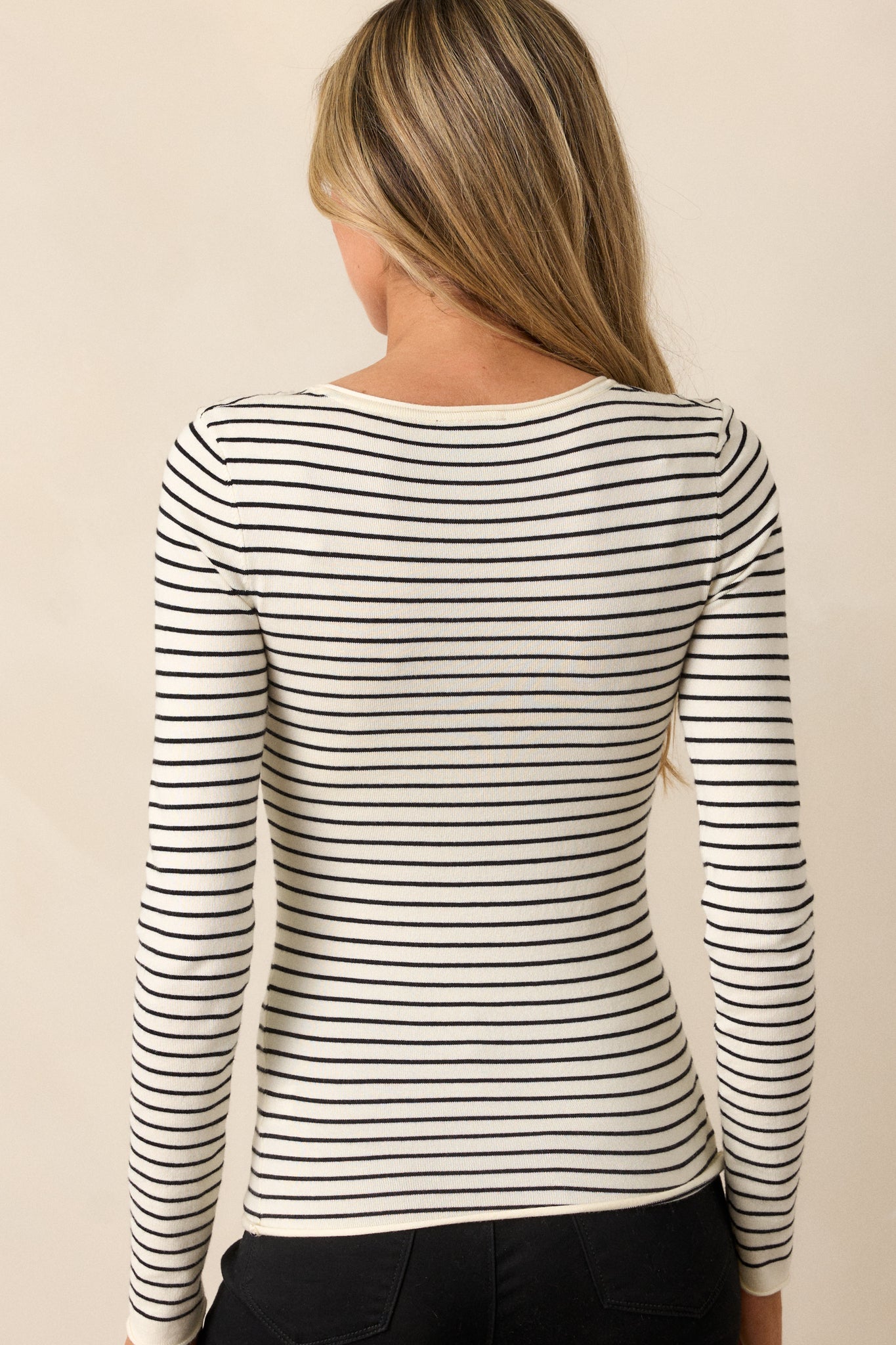 Rear view of the ivory top, highlighting the classic stripe design continuing across the back and the long sleeves.