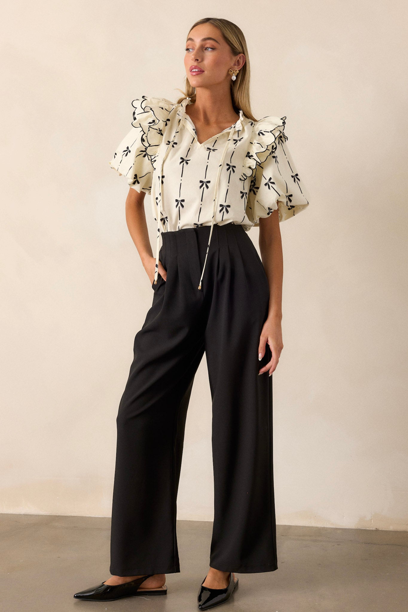 These black straight leg pants feature a high waisted design, a button zipper closure, slight pleats, functional hip pockets and a straight leg.