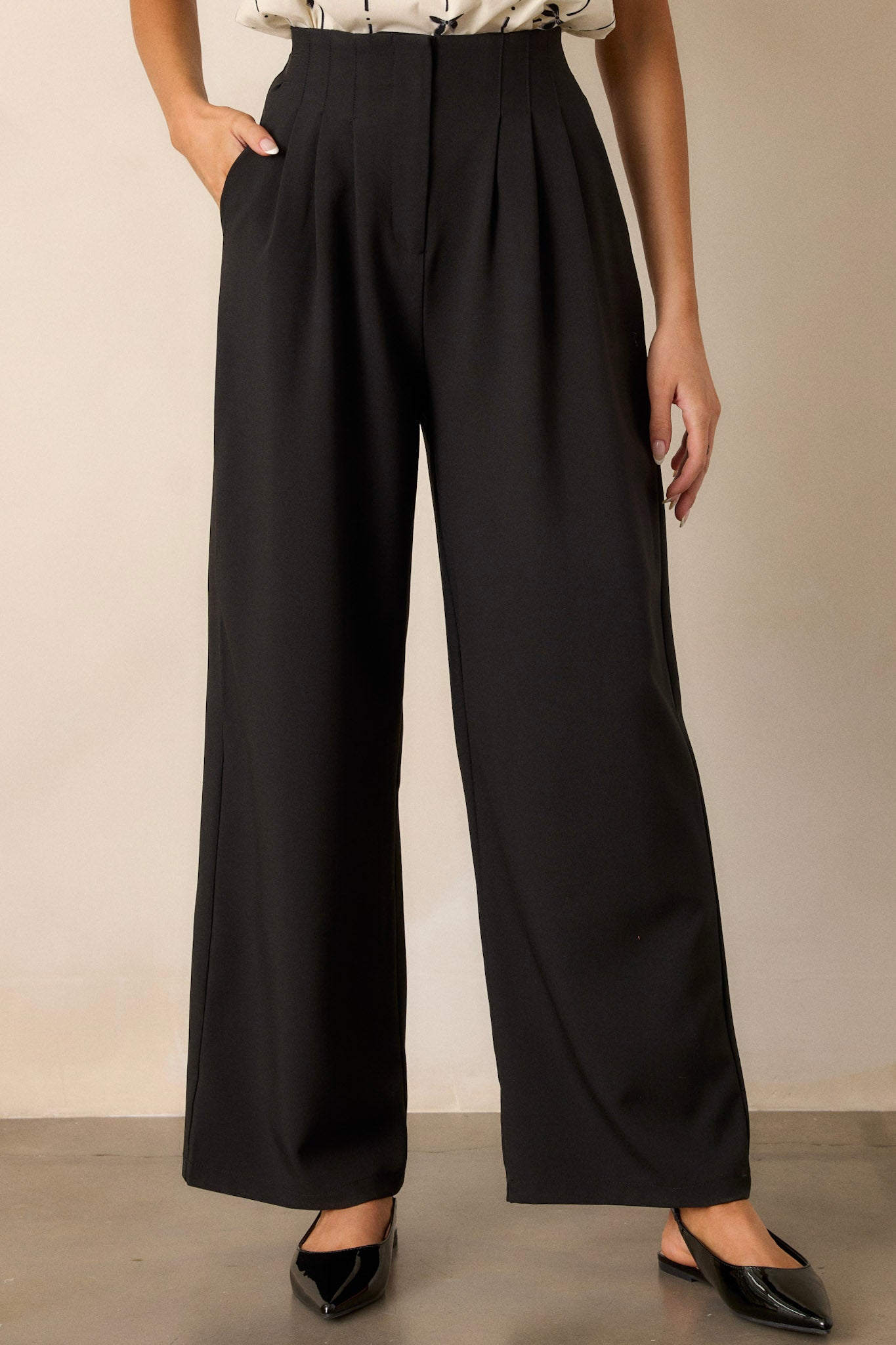 Front view of black straight leg pants featuring a high waisted design, a button zipper closure, slight pleats, functional hip pockets, and a straight leg.