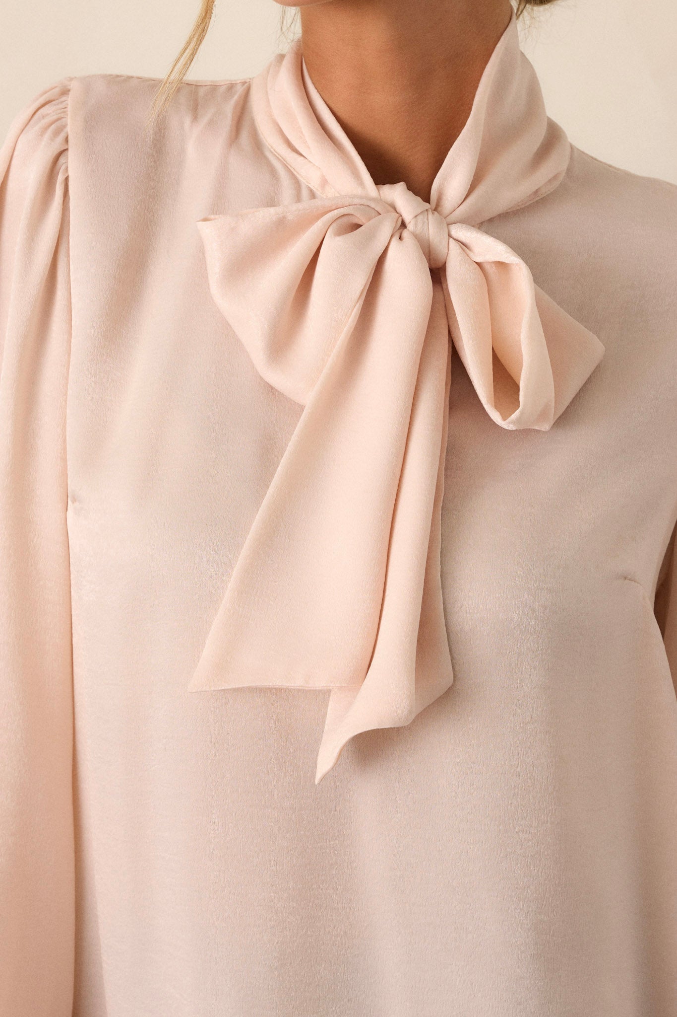 Close-up  view of a top highlighting the adjustable self-tie at the high neckline.