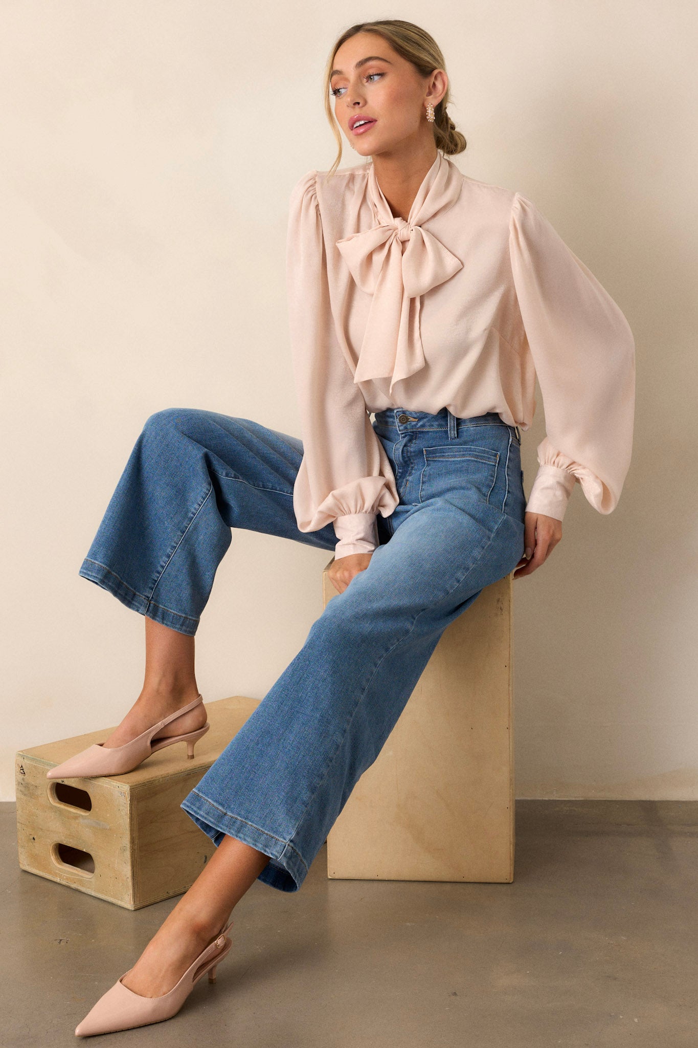 Full length view of a top with a high neckline, an adjustable self-tie, flowy balloon sleeves with two buttons at the cuff, and a relaxed fit