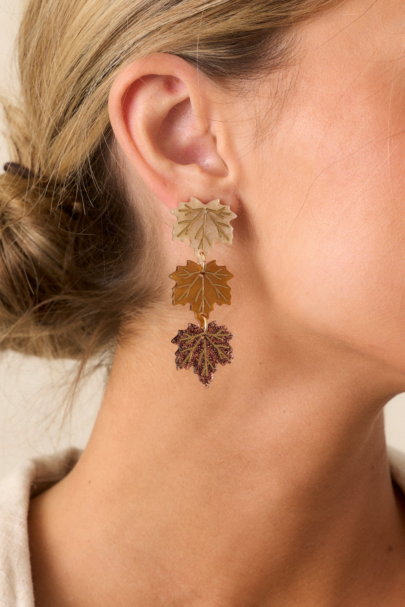 These brown earrings feature three acrylic leaf charms connected by gold jump rings, with gold leaf vein detailing, gold sparkle accents, and secure post backings.