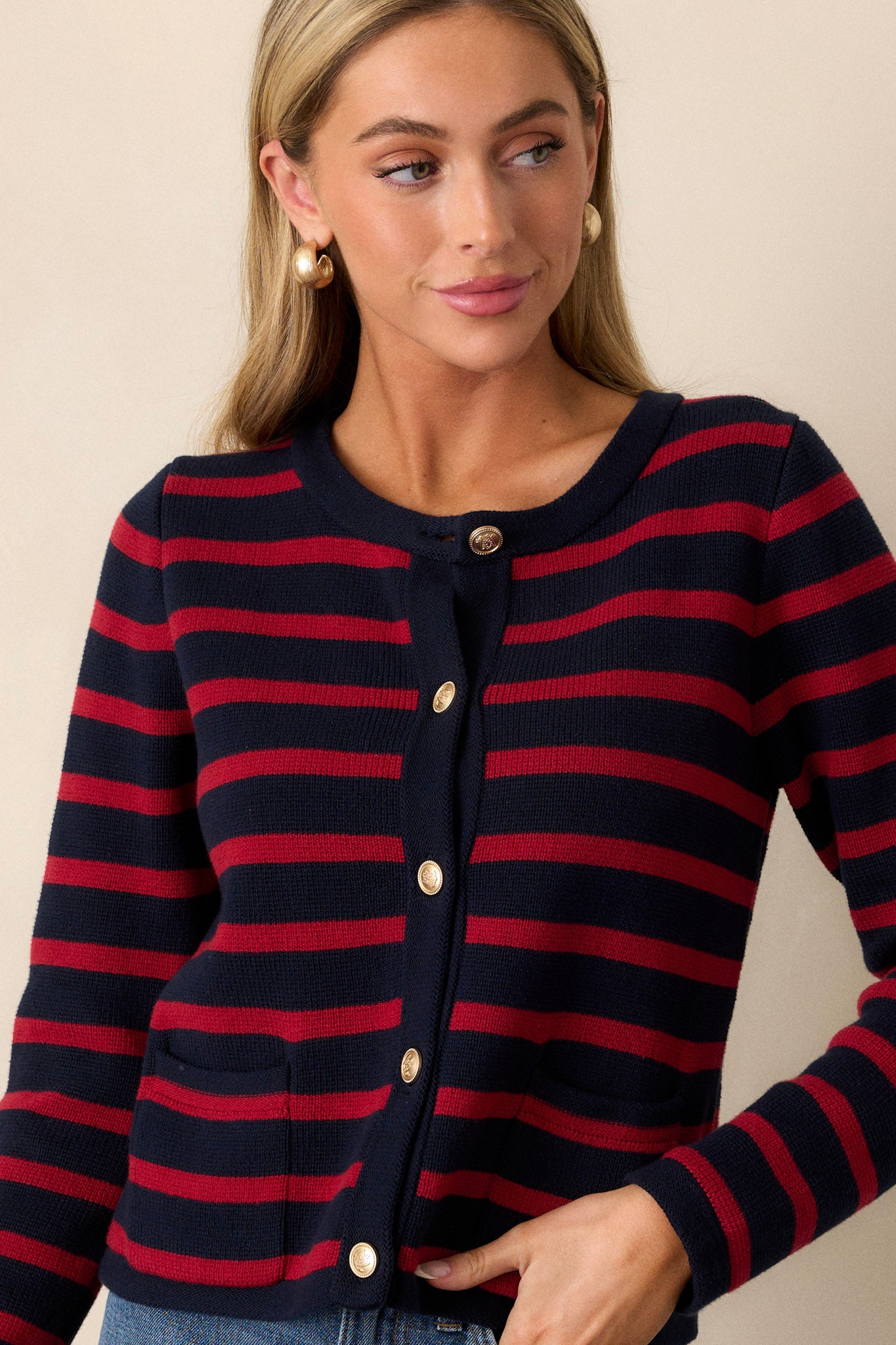 This cardigan features a crew neckline, a full button front, detailed gold buttons, and functional pockets.