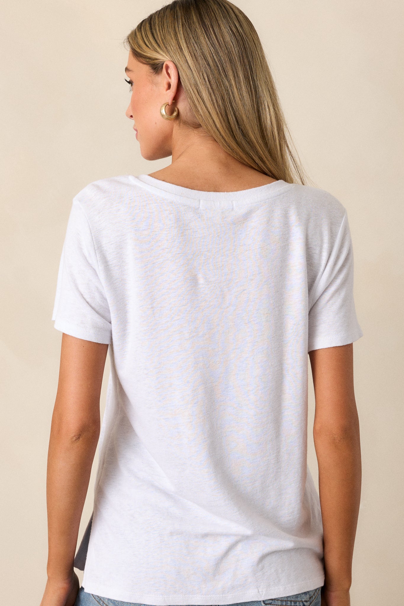 Back view of the white tee, displaying the relaxed fit and the clean lines of the split hemline from behind.





