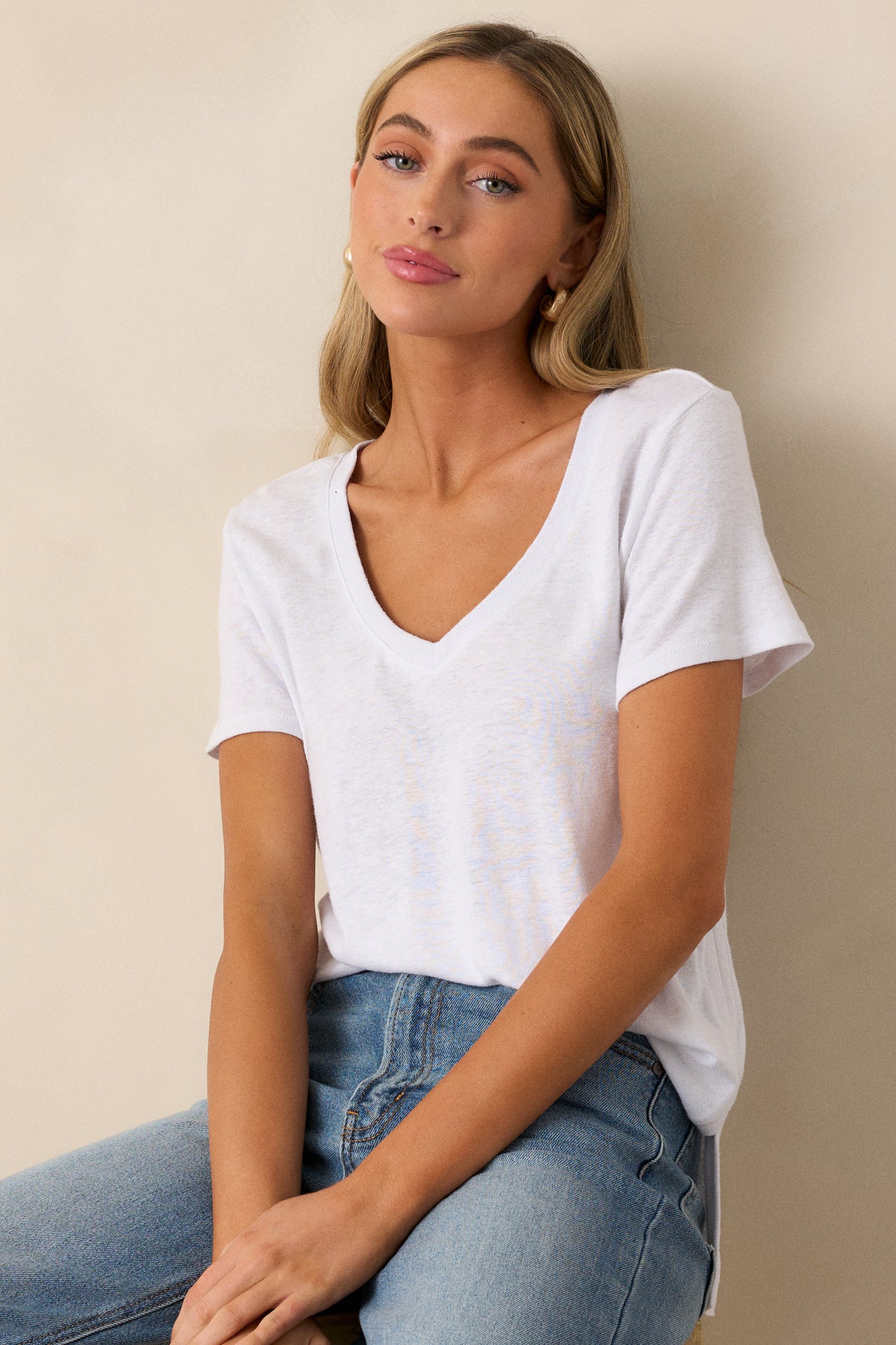 Full view of the white tee featuring a v-neckline, relaxed fit, and loose short sleeves, styled in a casual setting.