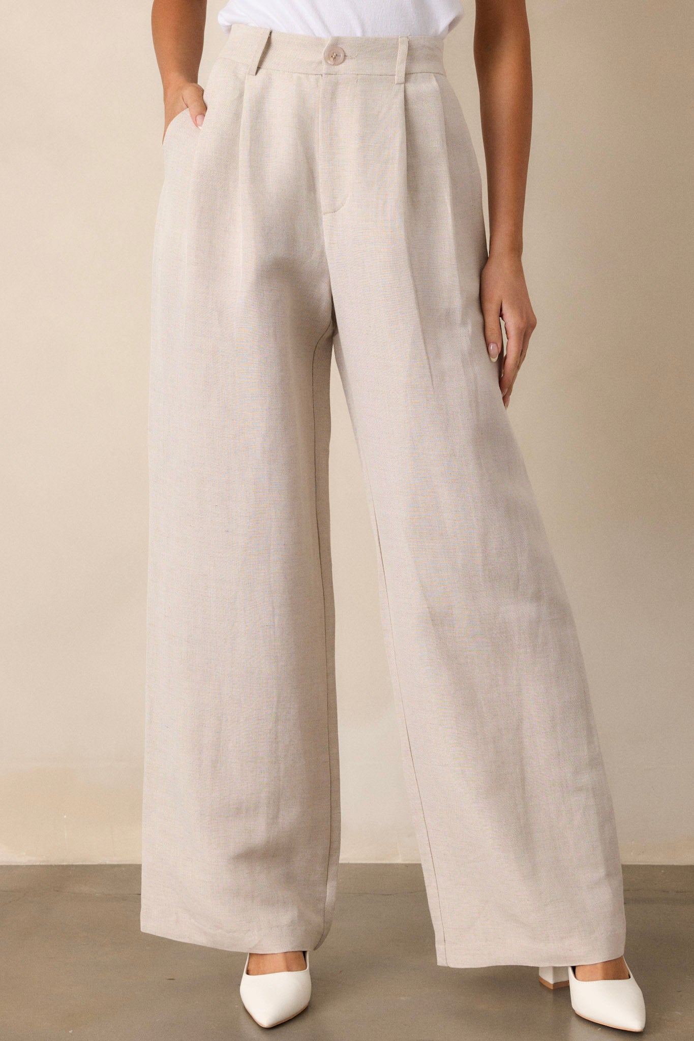 Front view of beige straight leg pants featuring a high waisted design, functional belt loops, slight pleats, functional hip pockets, and a straight leg.