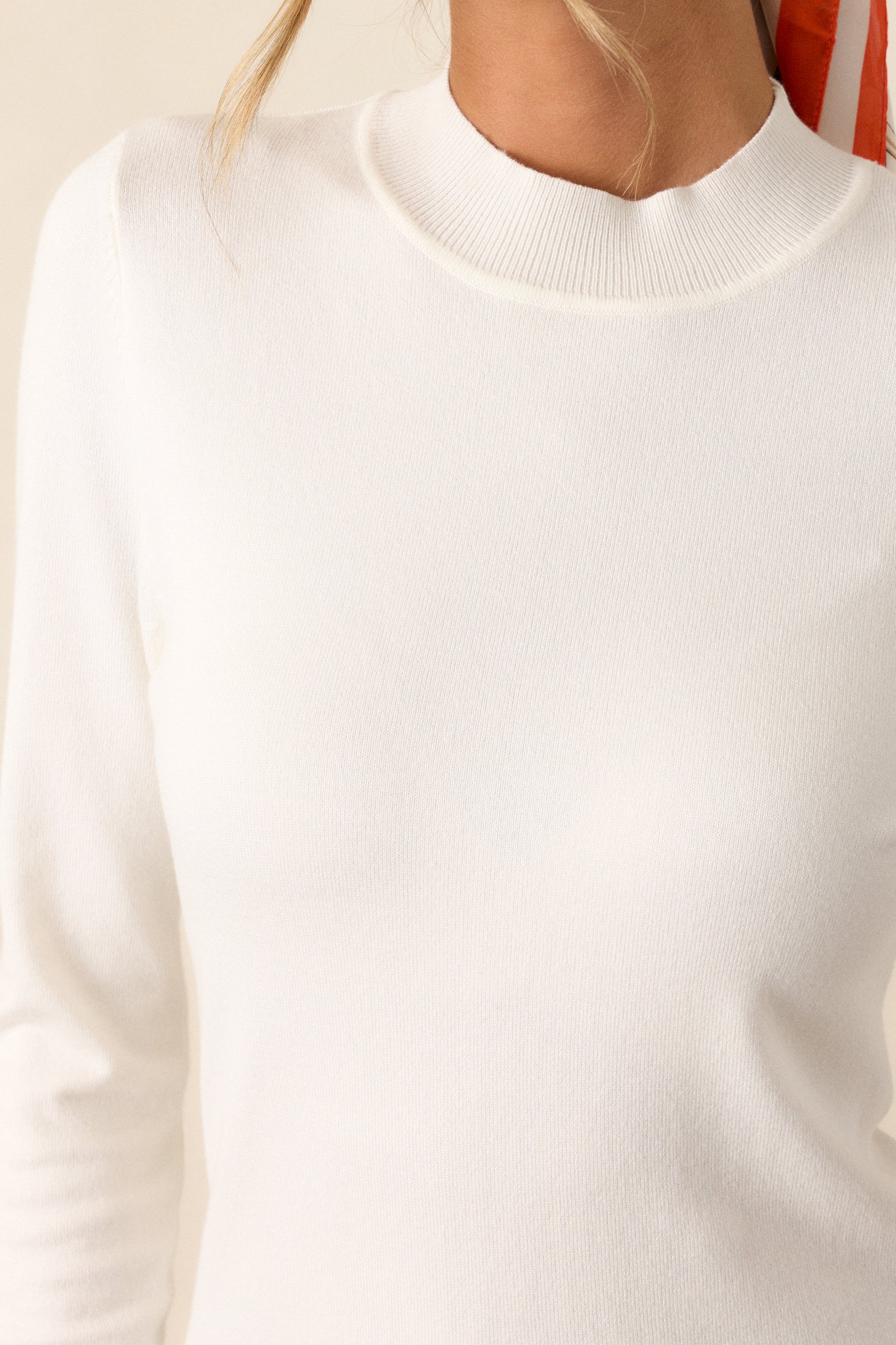 A close-up image focusing on the fabric texture of the ivory sweater, highlighting its lightweight and breathable quality.