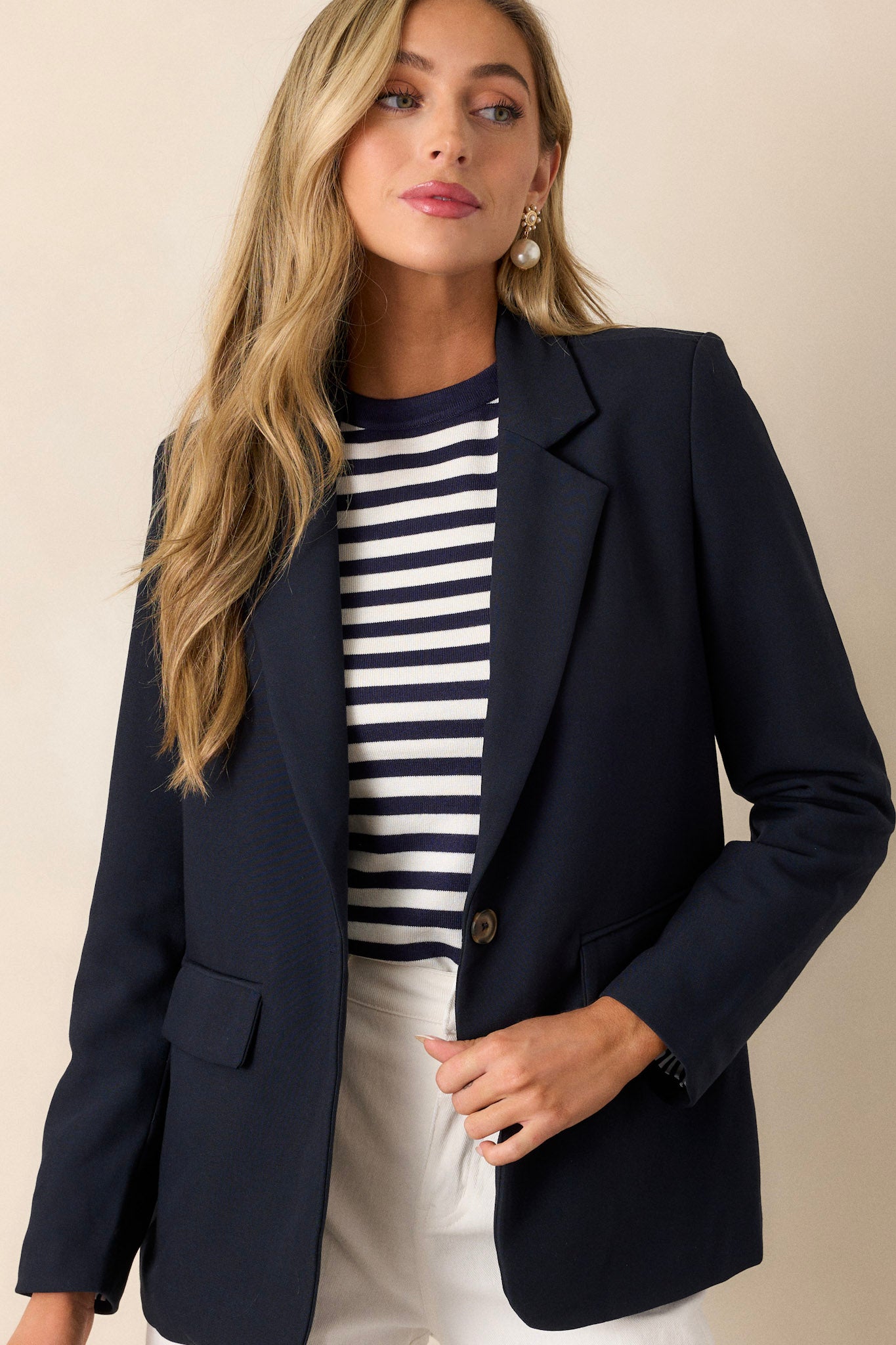 This navy blazer features a collared neckline, a middle button closure, padded shoulders, a floral lining, and long sleeves.