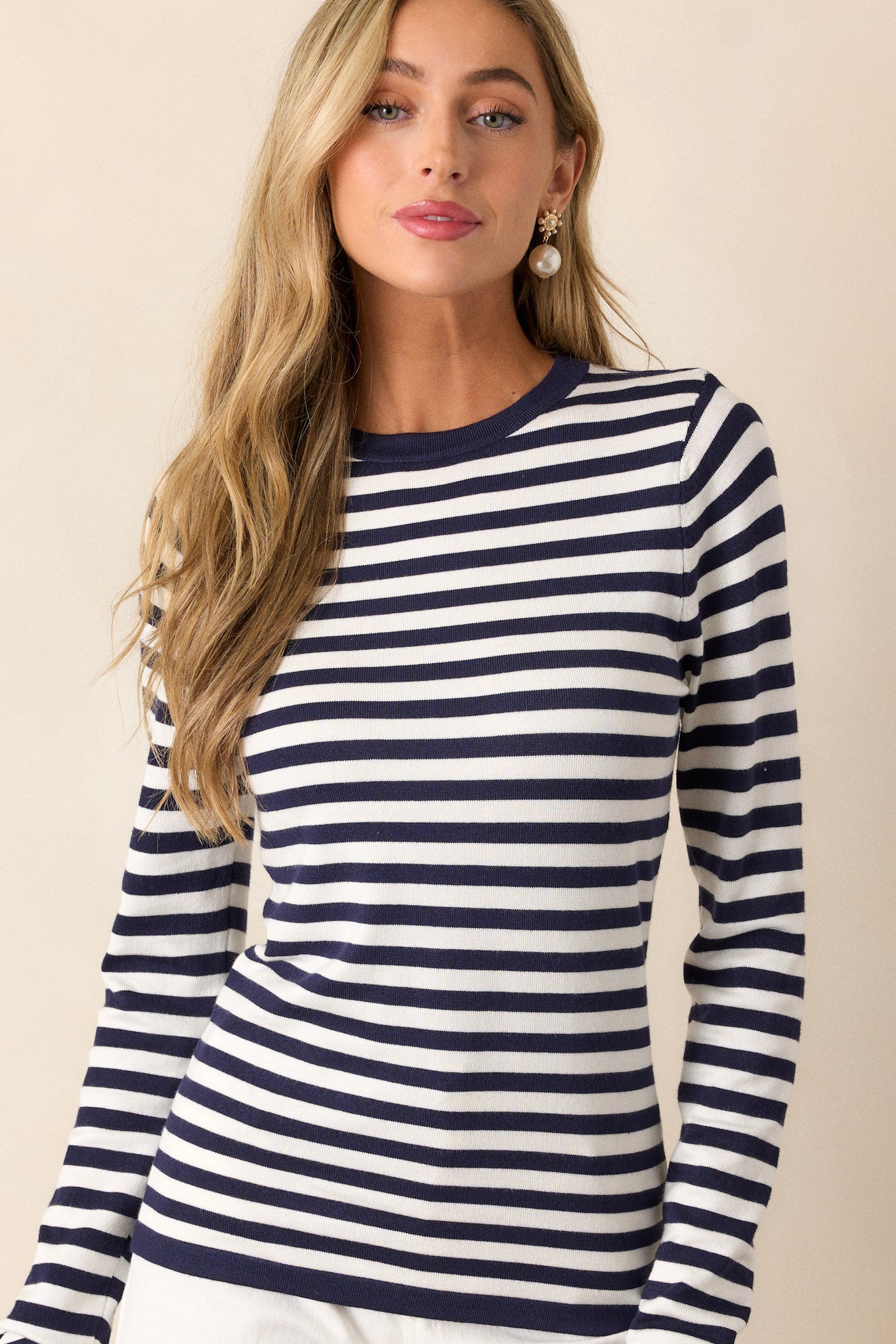 This ivory top features a crew neckline, long sleeves, a navy stripe pattern, a light weight fabric, and a close fit.