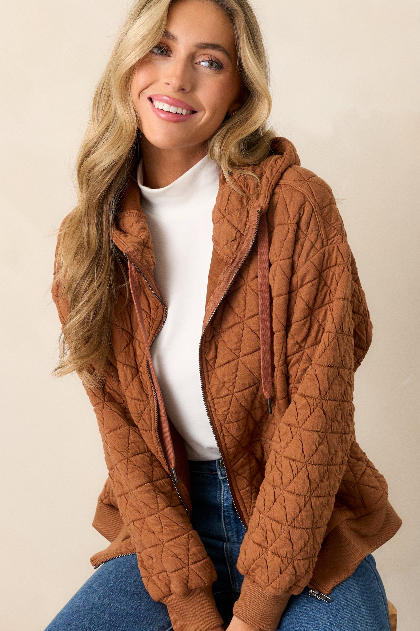 Action shot of the copper quilted jacket displaying the structure and movement, highlighting the high neckline, quilted design, and thick hem with cuffed long sleeves.