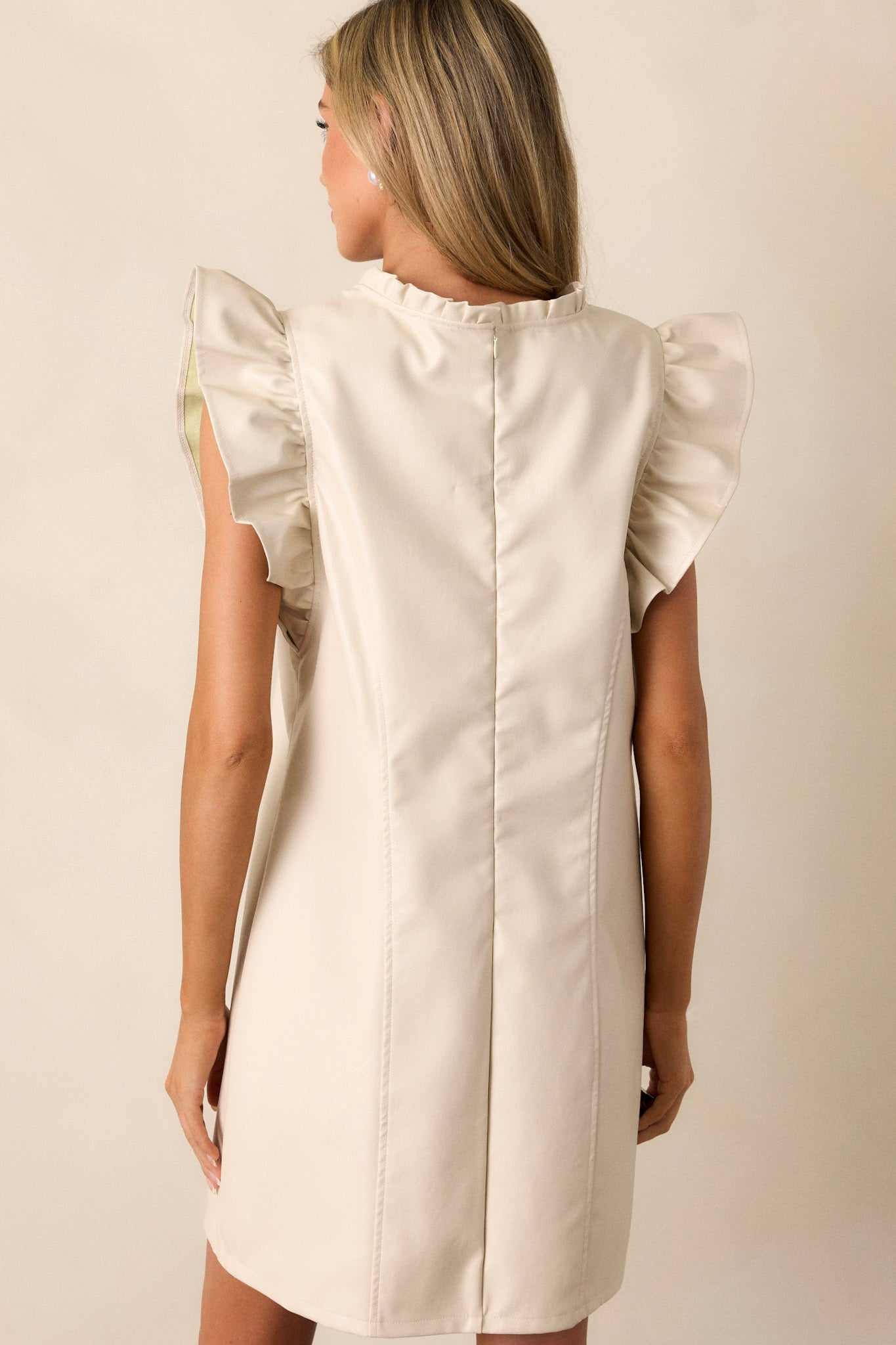 Back view of this ruffle sleeve dress featuring a ruffled high neckline, bowtie detailing, a relaxed fit, ruffled short sleeves and a discrete back zipper.