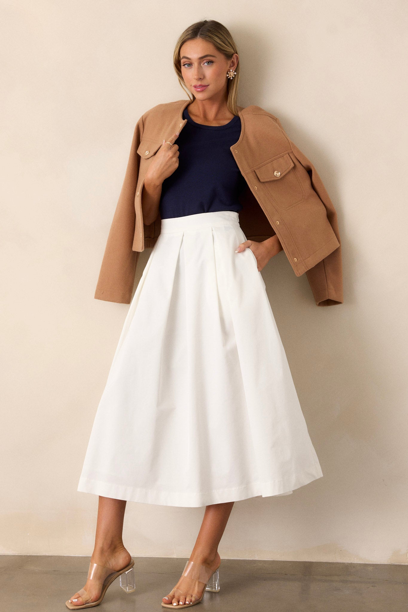 Full body view of this white midi skirt that features a high waisted design, a discrete side zipper, and a thick waistline.