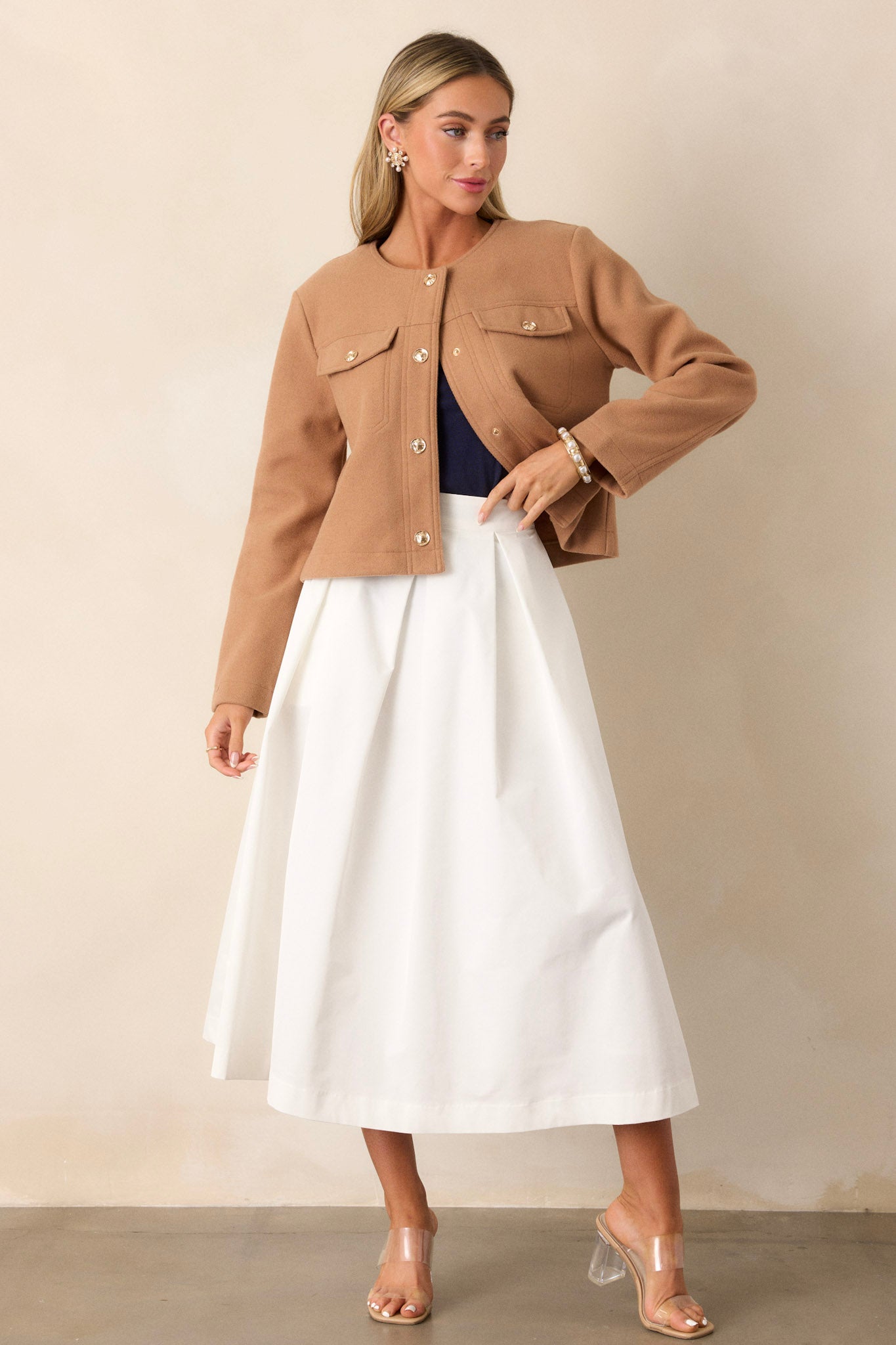 Angled full body view of this white midi skirt that features a high waisted design, a discrete side zipper, and a thick waistline.