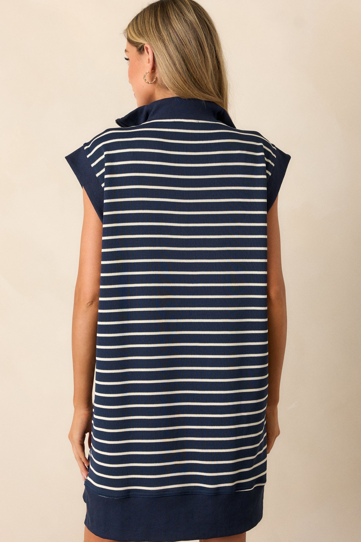 Back view of this navy and white striped dress  featuring a collared neck, quarter-zip, cap sleeves, and pockets.