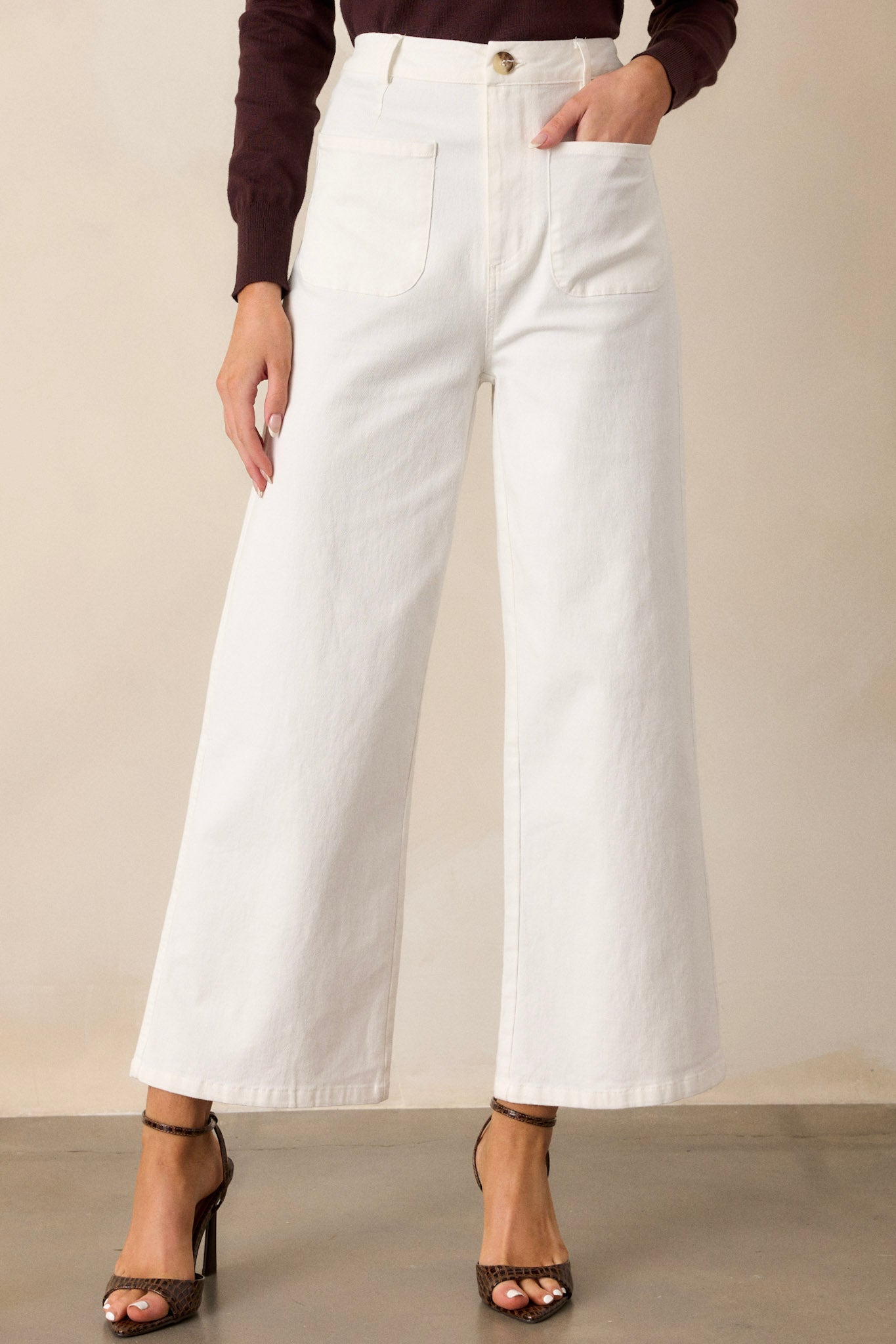 Front view of ivory jeans featuring a high waisted design, classic button & zipper closure, belt loops, functional front pockets, faux back pockets, and a wide leg design.