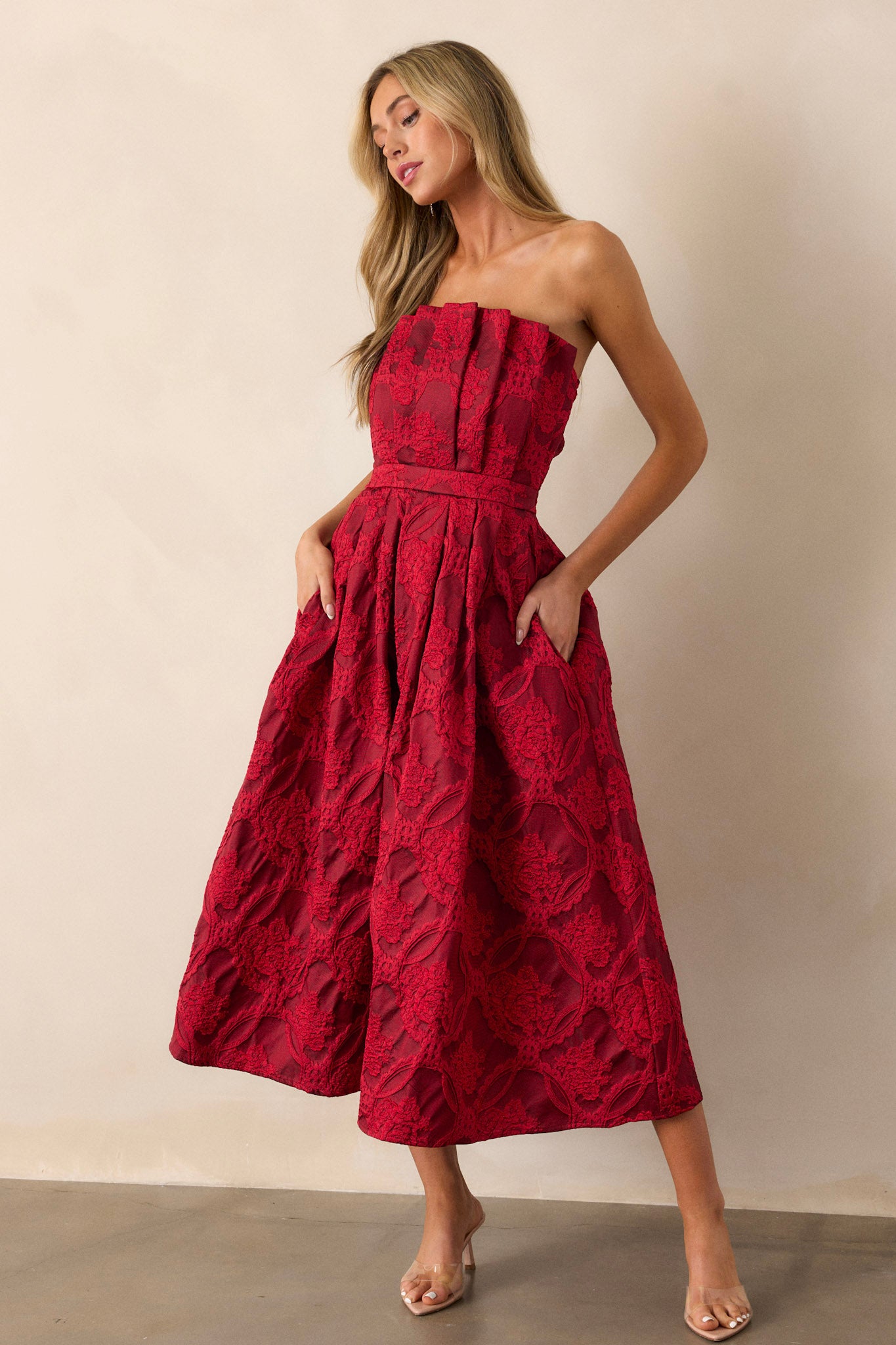 Close up of the pleated, jacquard bodice on this strapless, red , midi dress. 