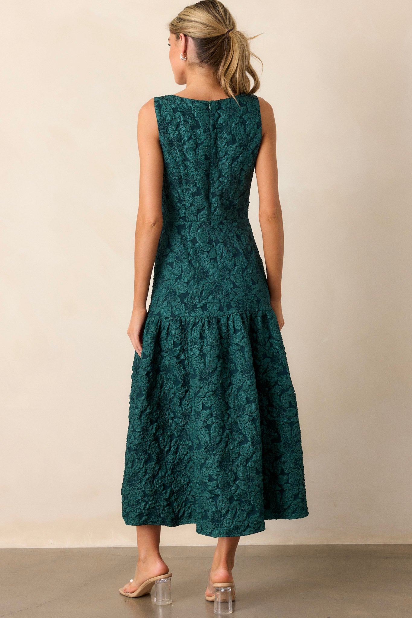 Back view of the green dress, showcasing the discrete zipper along the smooth jacquard fabric and the sleeveless back design.