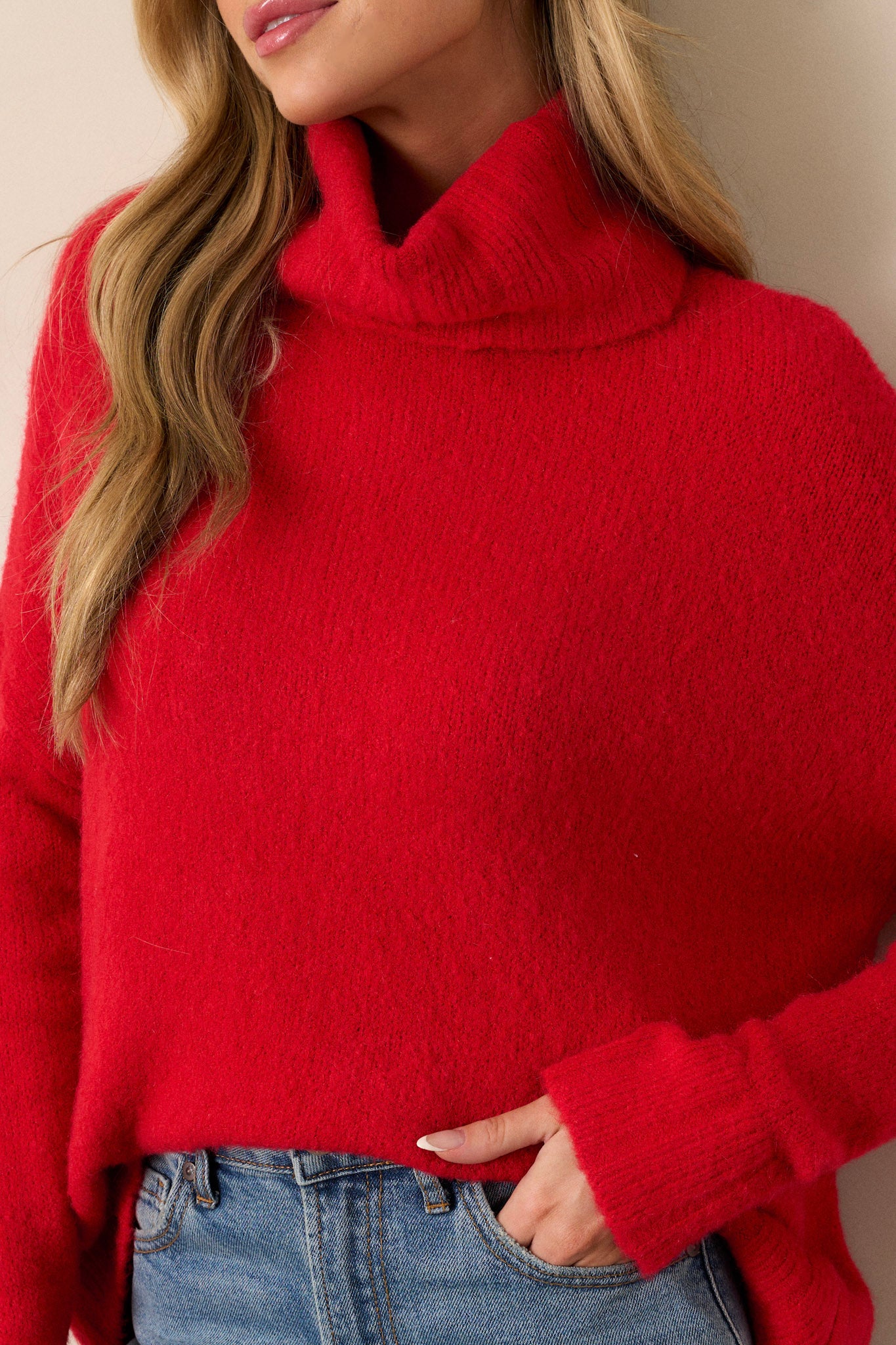 Close up view of this sweater that features a very light eyelash knit design, a turtle cowl neckline, extremely dropped shoulders, and a slight high low hemline.