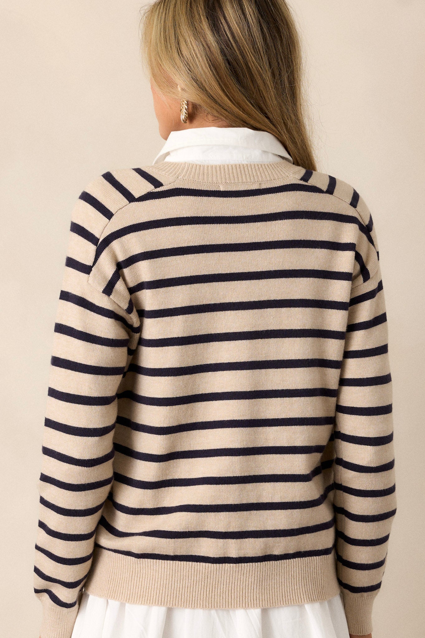 Back view of a beige long sleeve highlighting the horizontal stripe pattern, thick ribbed hem, and cuffed long sleeves.