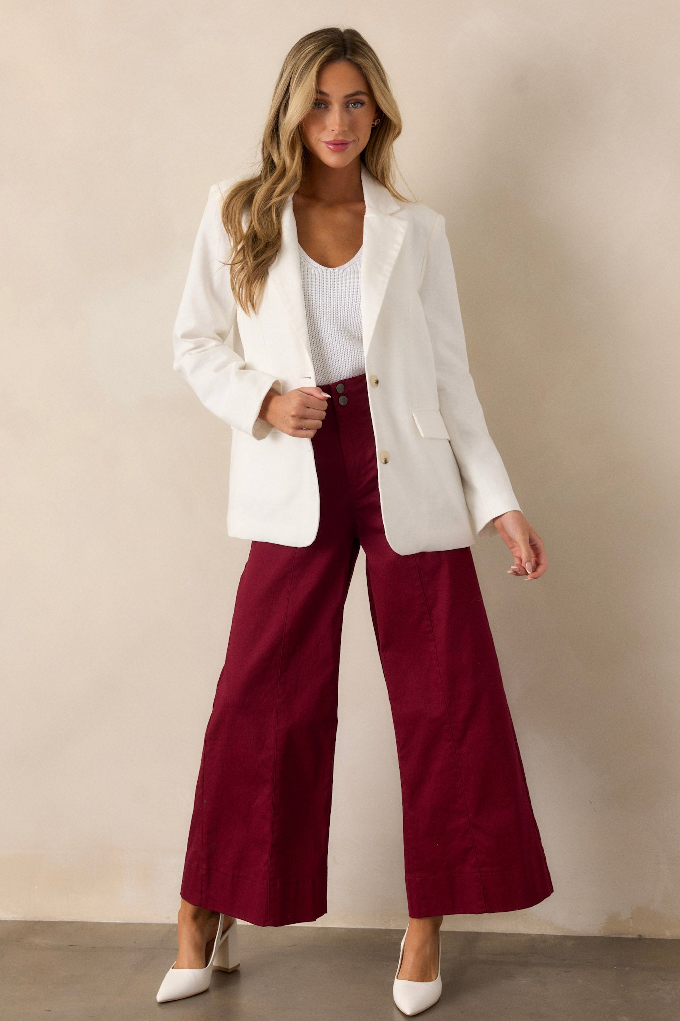 Full length view of burgundy pants featuring a high waisted design, a button zipper closure, functional rectangular hip pockets, and a wide leg