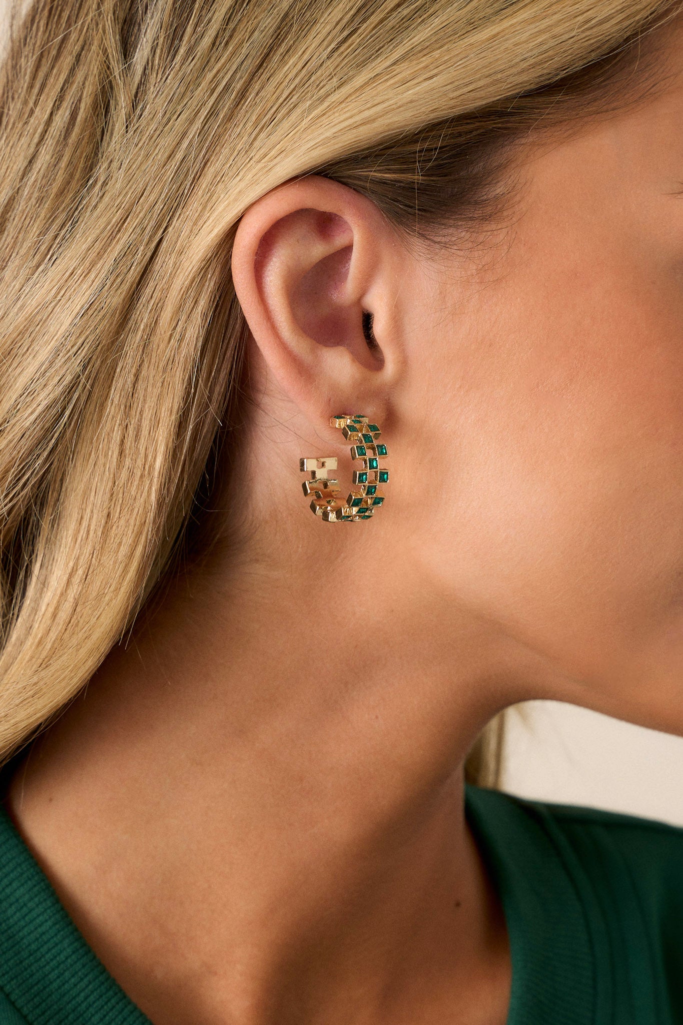 These earrings feature a incomplete hoop design, checkered green rhinestones, gold hardware, and secure back postings.