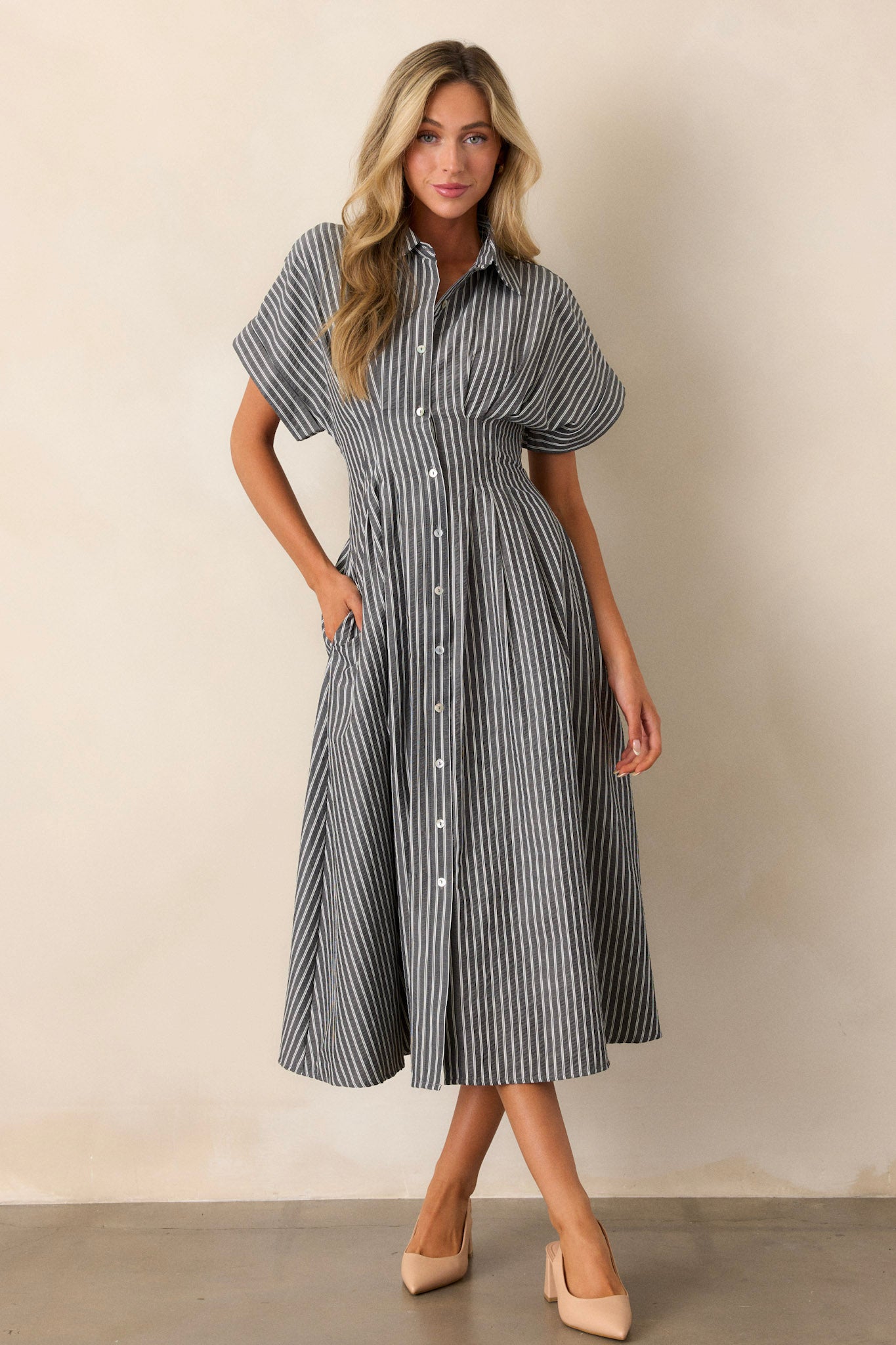 A full-body image of the black dress highlighting the top’s stripe pattern, buttoned front, and short-sleeved design.