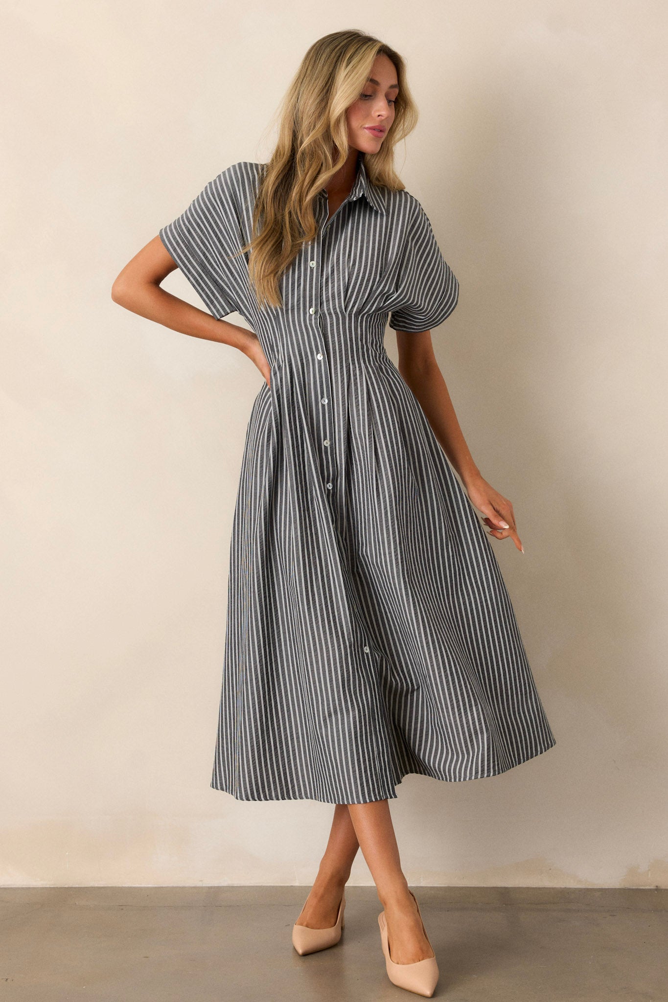 A full-body image of the black dress highlighting the top’s stripe pattern, buttoned front, and short-sleeved design.