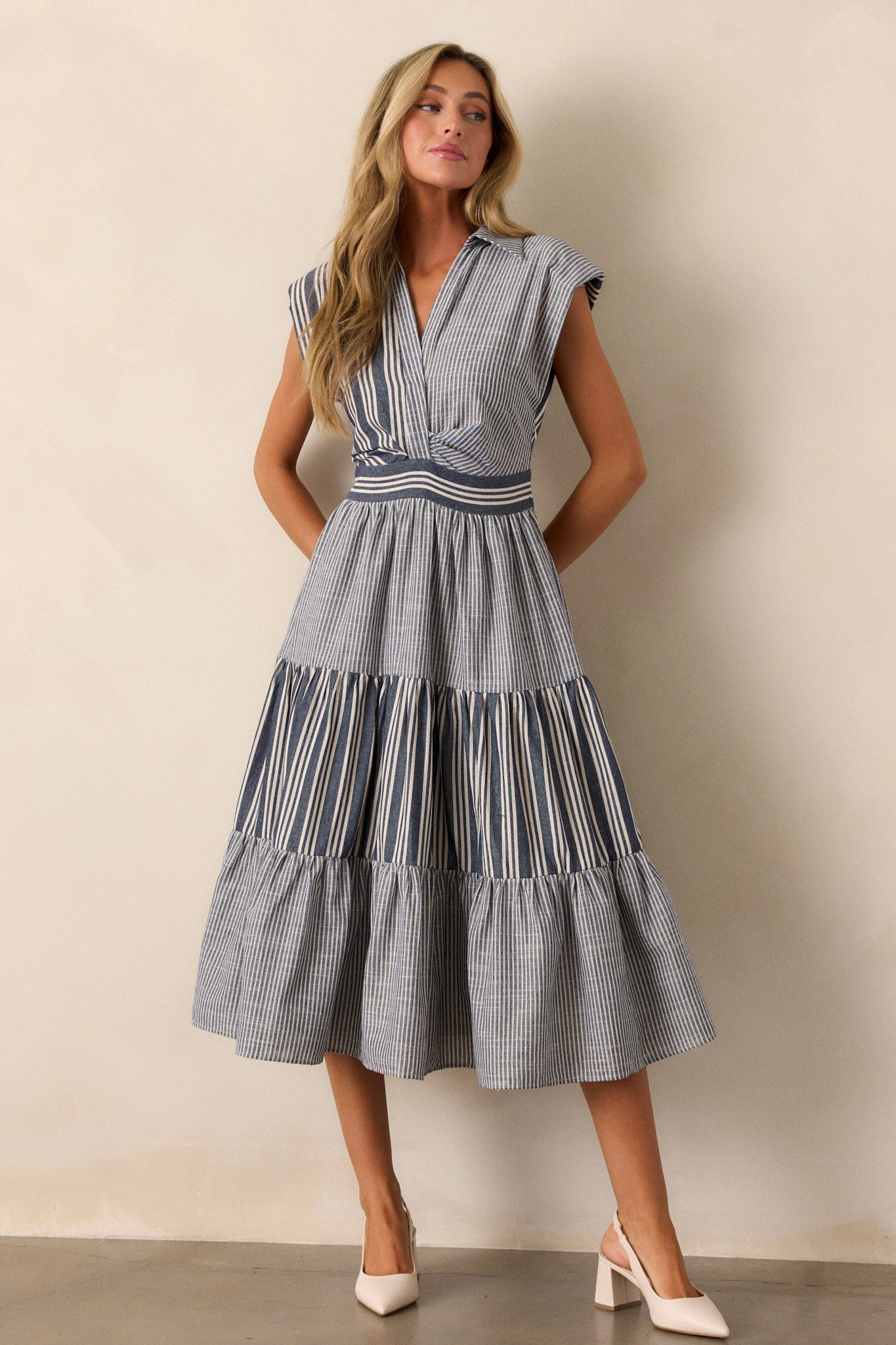 Front view of a navy dress, highlighting the striped pattern across the bodice, cap sleeves, and a collared neckline with visible buttons.