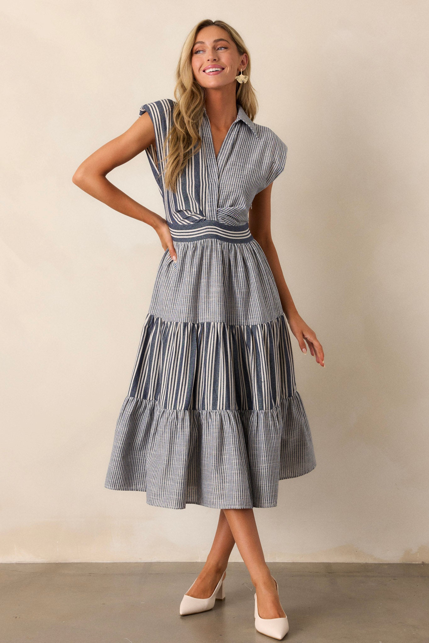 Front view of a navy dress, highlighting the striped pattern across the bodice, cap sleeves, and a collared neckline with visible buttons.