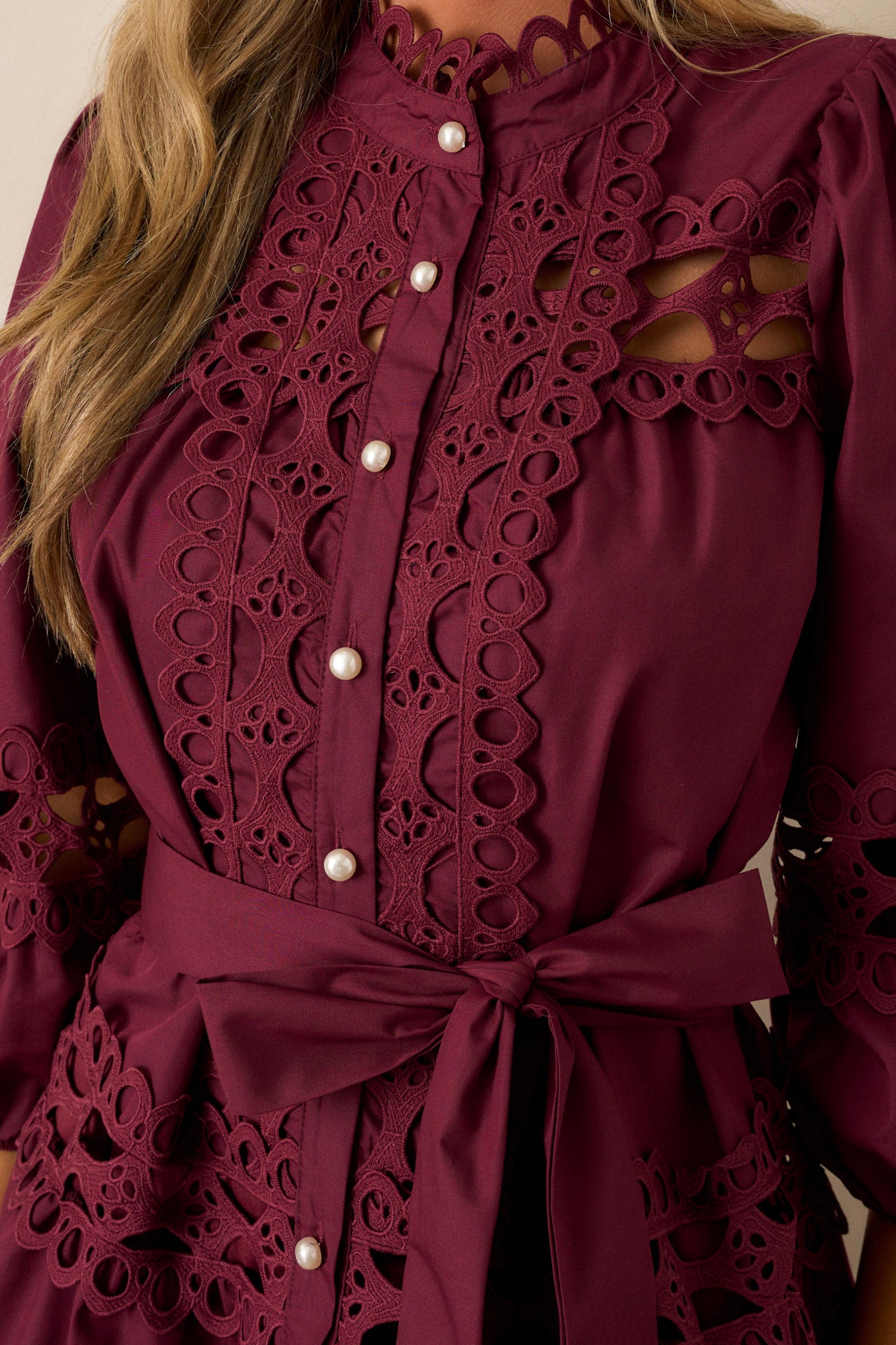 Close up of the eyelet and pearl detailing on the this plum mini dress.