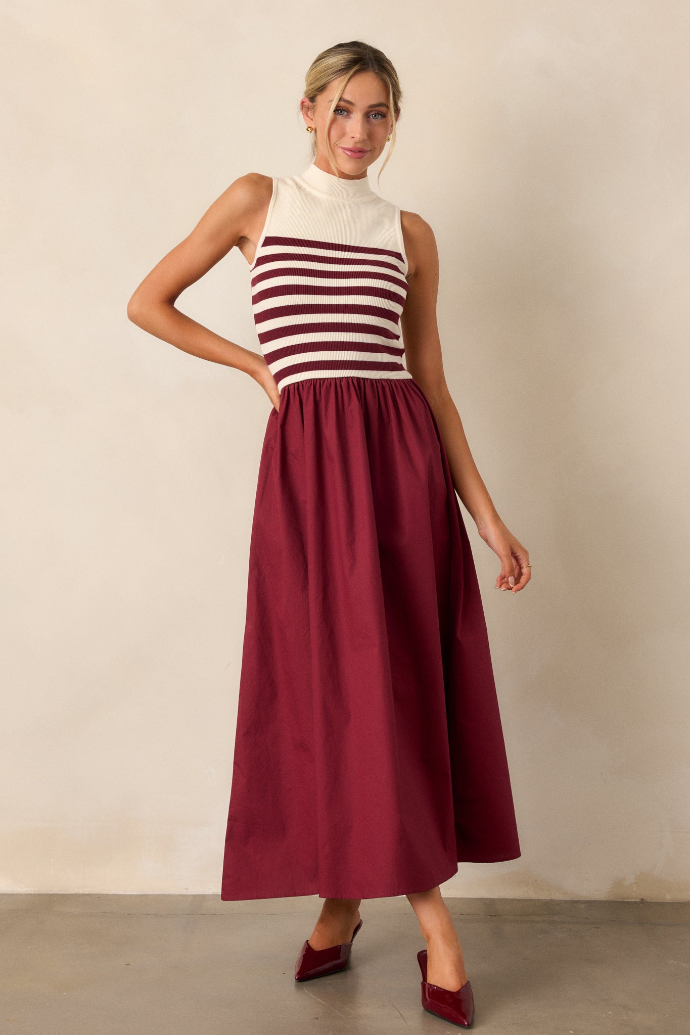 This burgundy stipe maxi dress features a high neckline, a striped sweater bodice, and a flowy skirt.