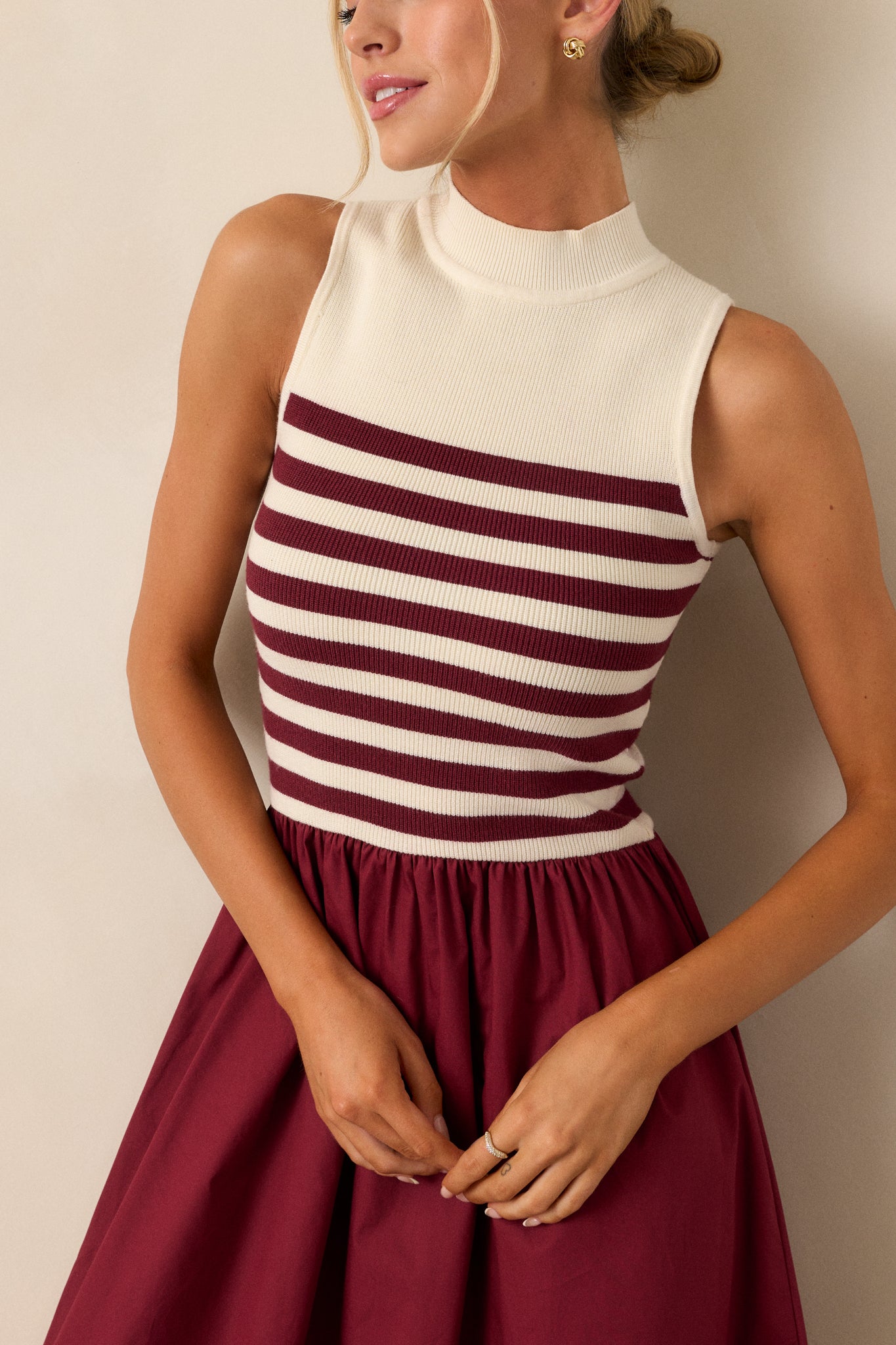 Close up view of this burgundy stripe maxi dress that features a high neckline, a striped sweater bodice, and a flowy skirt.