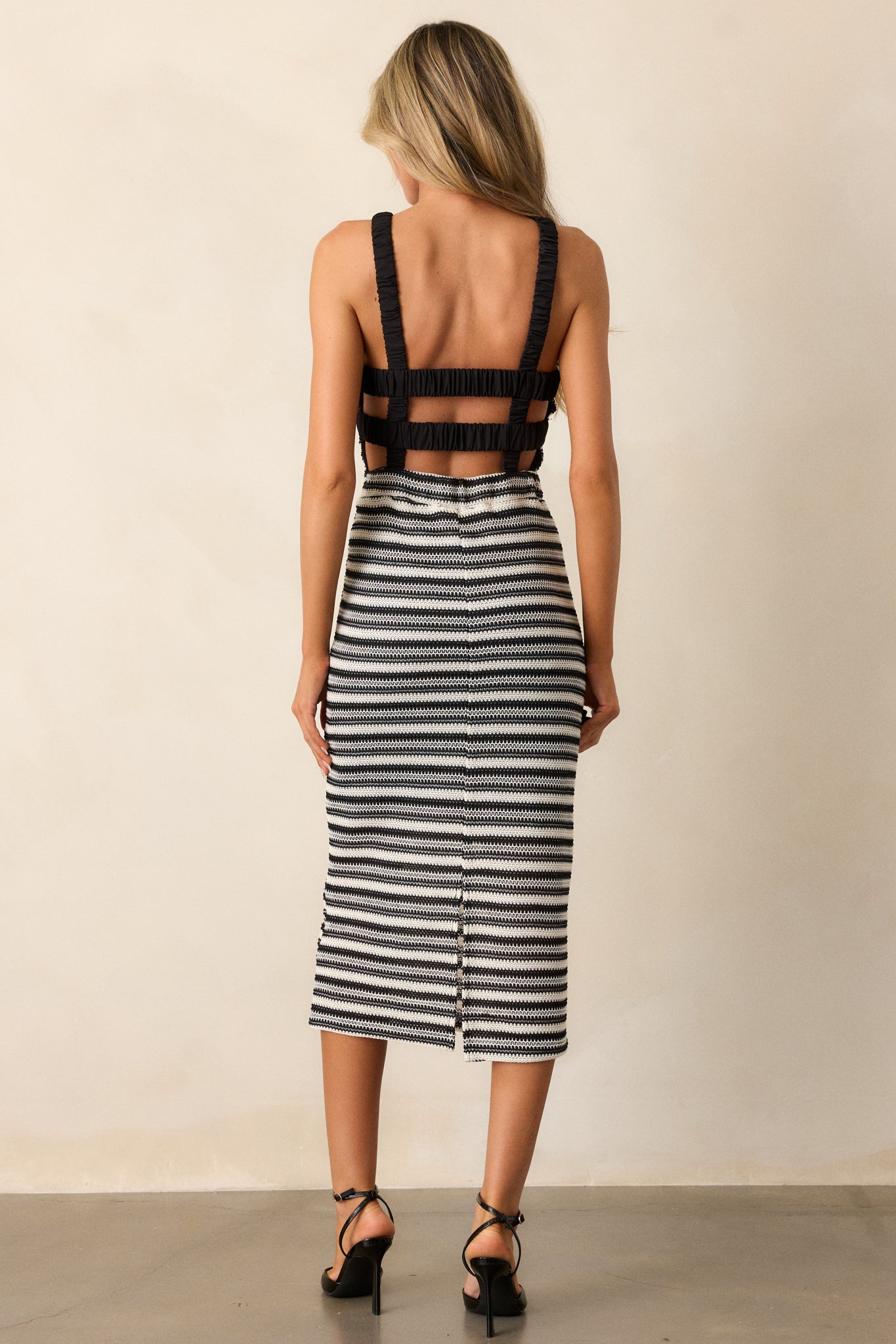 Rear view of the black knit midi dress, highlighting the low back and the continuation of the horizontal stripes along the back.