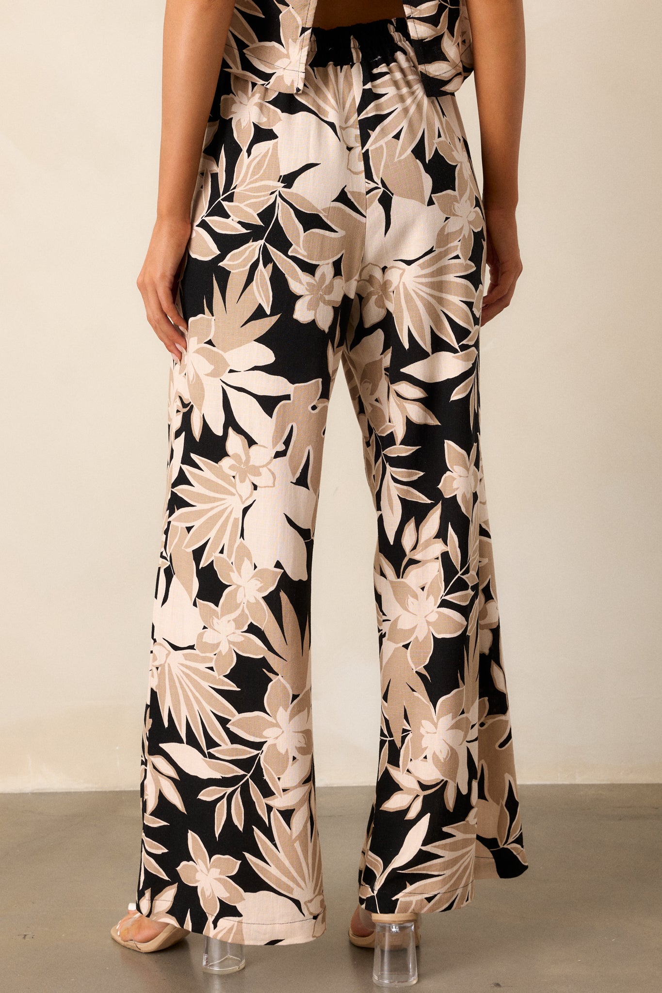 Back view of the taupe pants, showing the high-waisted design, elastic waistband, and floral pattern from behind.