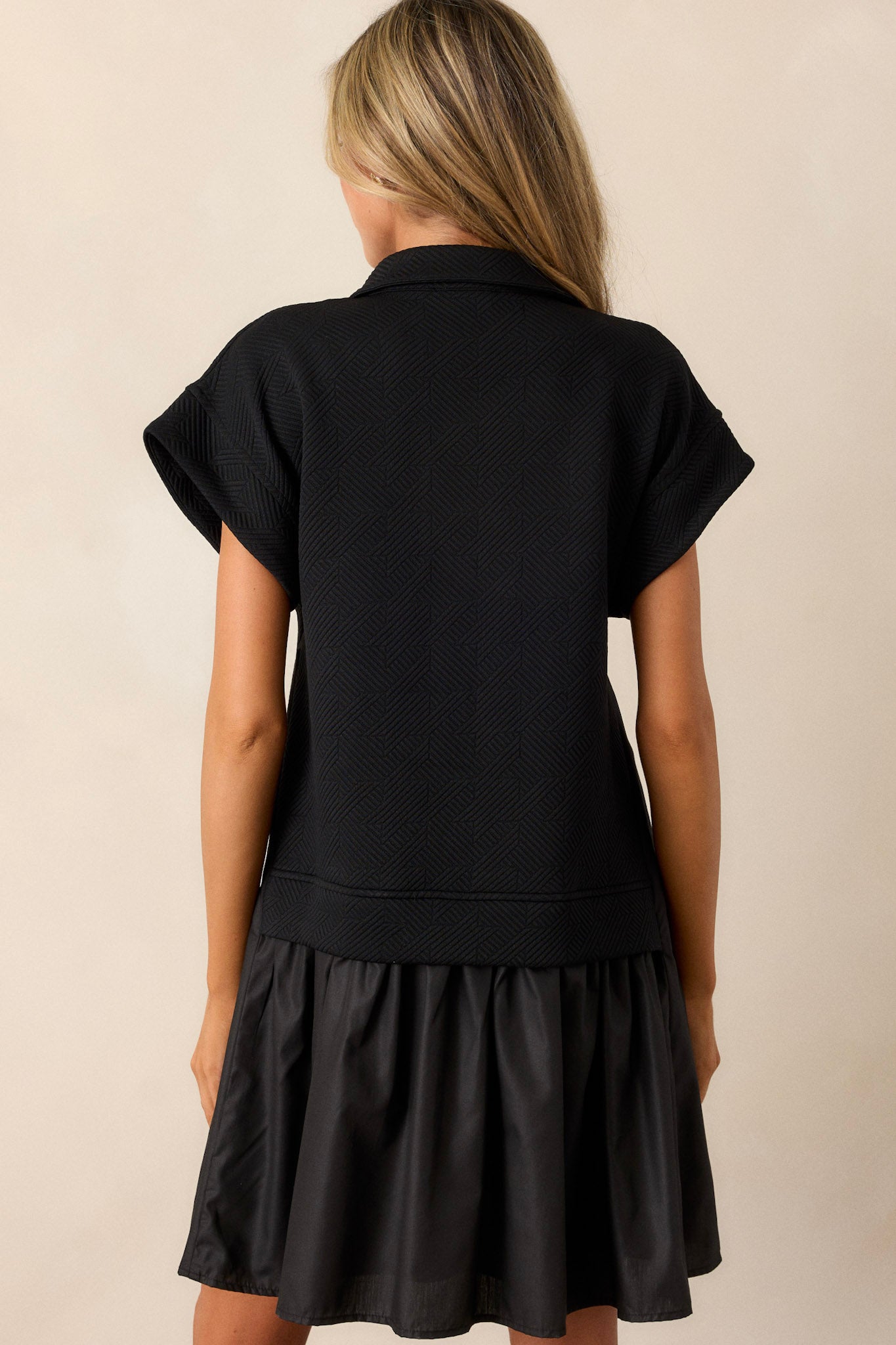 Back view of a black quilted dress highlighting the overall fit, quilted bodice, and tiered design.