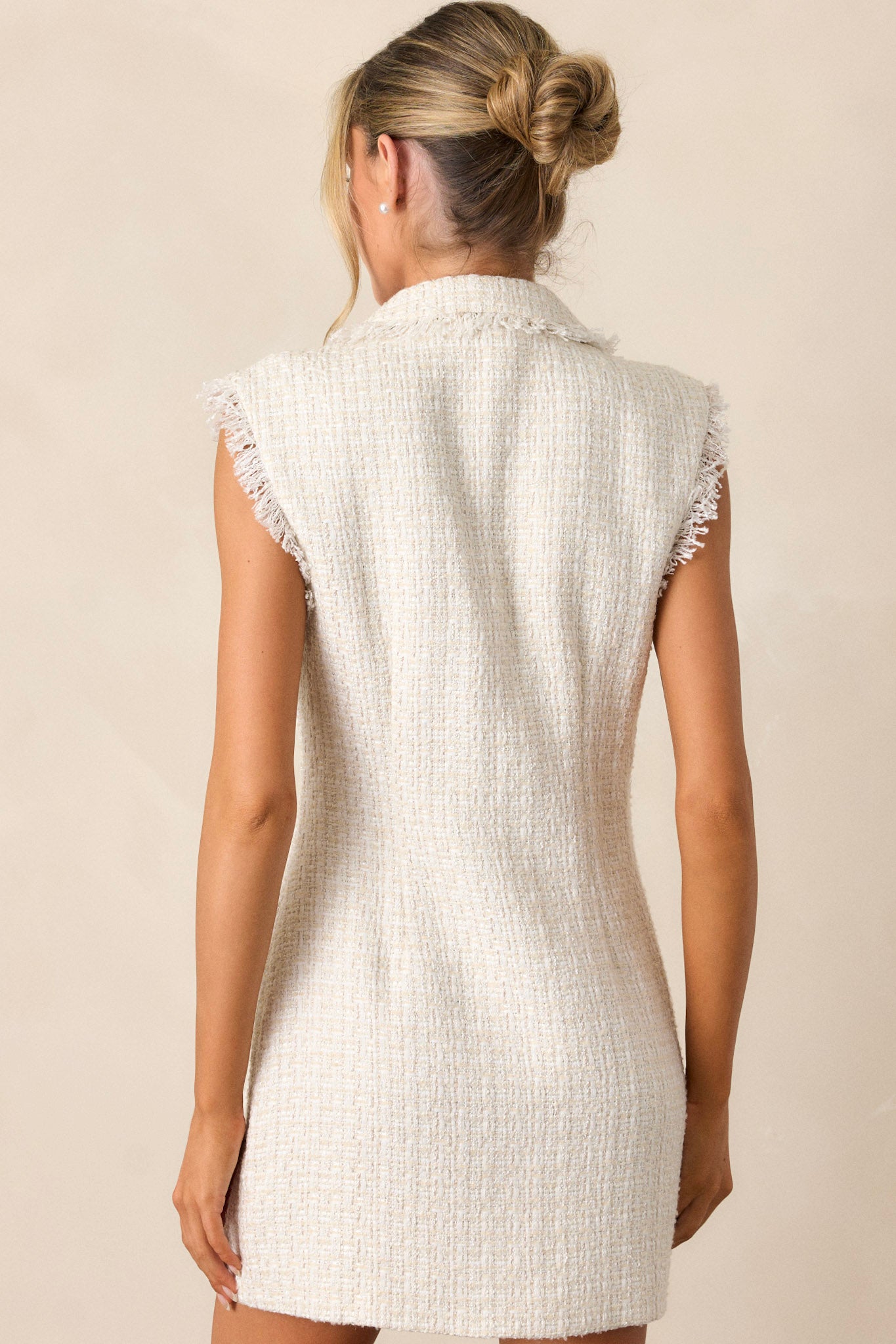 A view of the back of the ivory mini dress, displaying the sleeveless tailored silhouette and clean lines of the mini-length design.