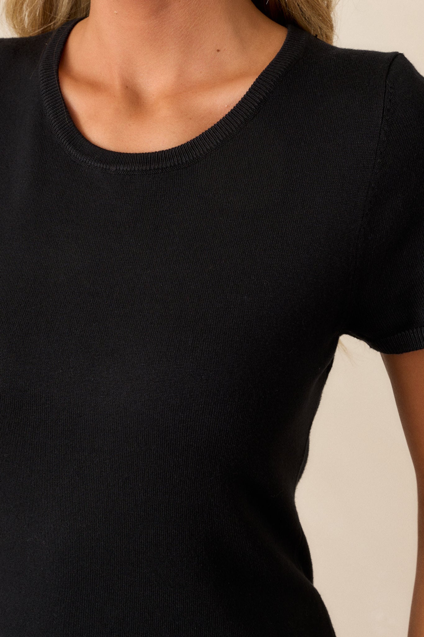 Detailed close-up of the ribbed hem and the smooth, cozy texture of the black sweater fabric.