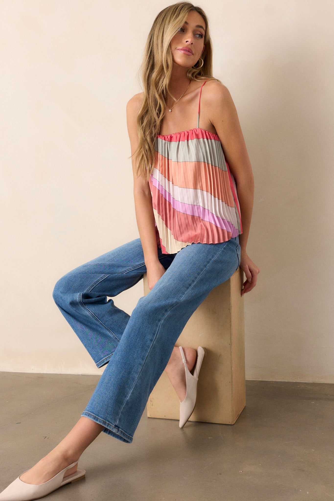 Front angled view of a pink coral top featuring a square neck, a pleated design, thin adjustable straps, and a slightly cropped hemline