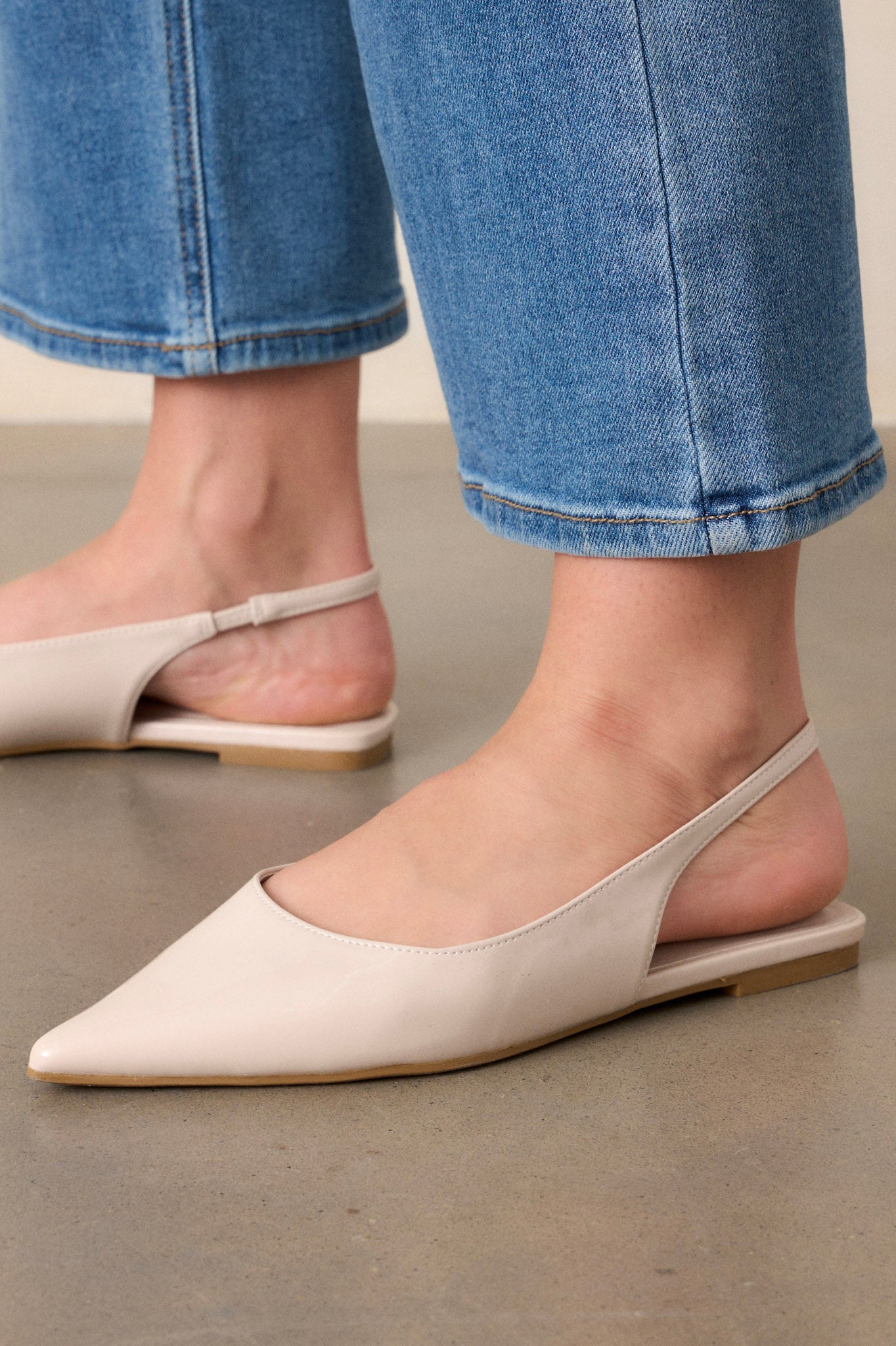 These ivory flats feature a pointed toe, a faux leather texture, a slingback-style strap, and a sleek ivory color.