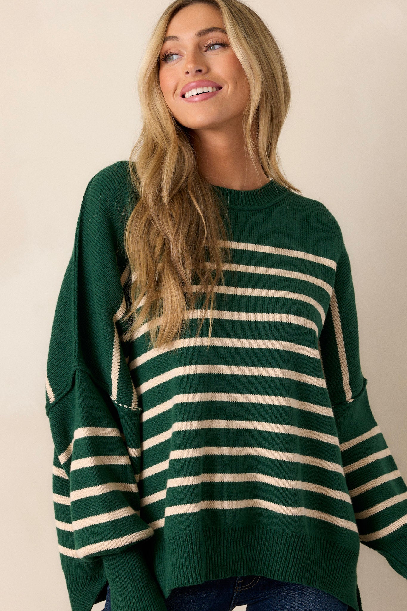 Front view of a green stripe sweater showcasing the ribbed neckline, oversized fit, ribbed hem with side slits, and horizontal stripe pattern.