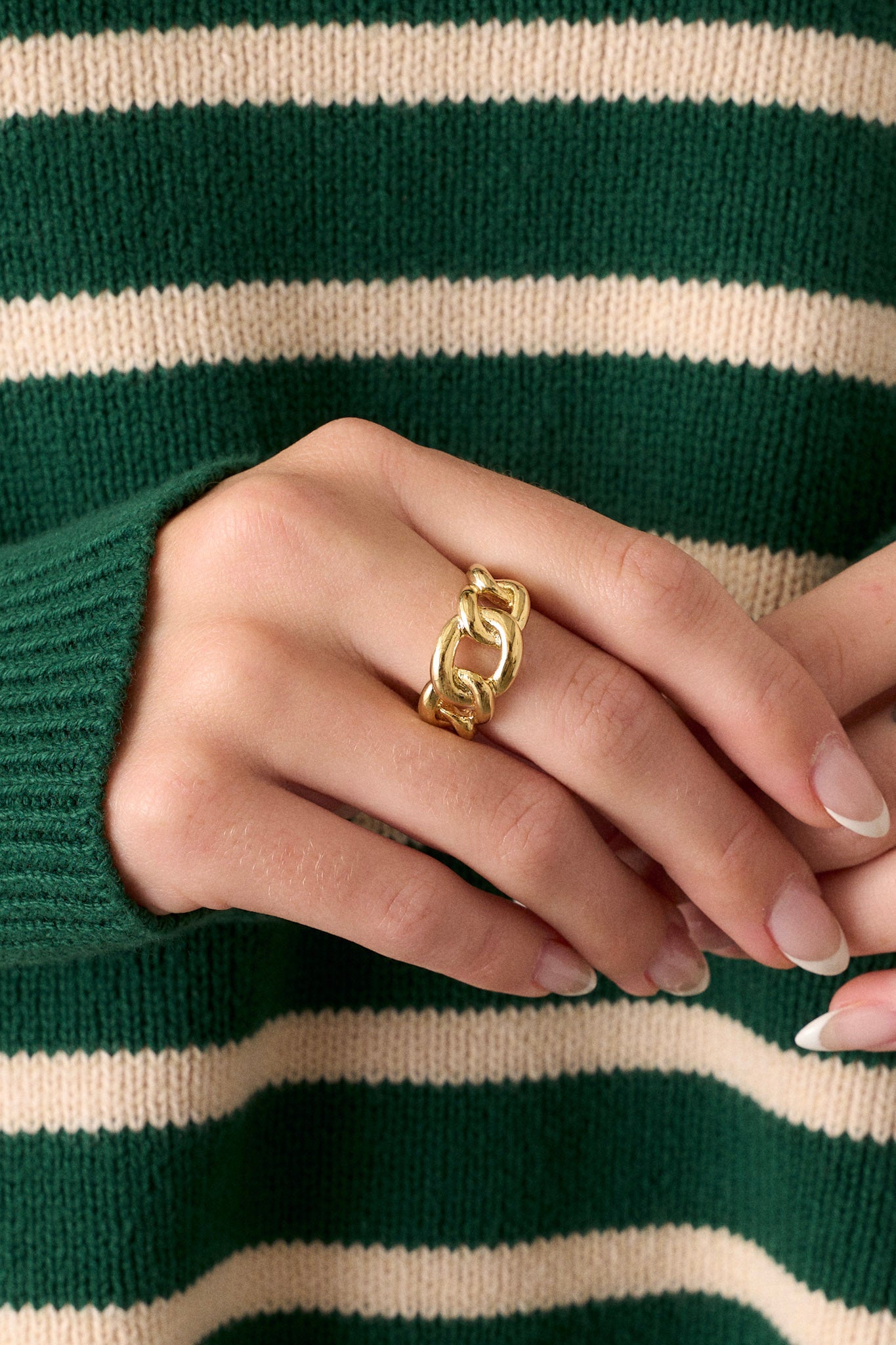 Close-up view of this ring featuring gold hardware, a chain link design, adjustable band, and secure post backings.