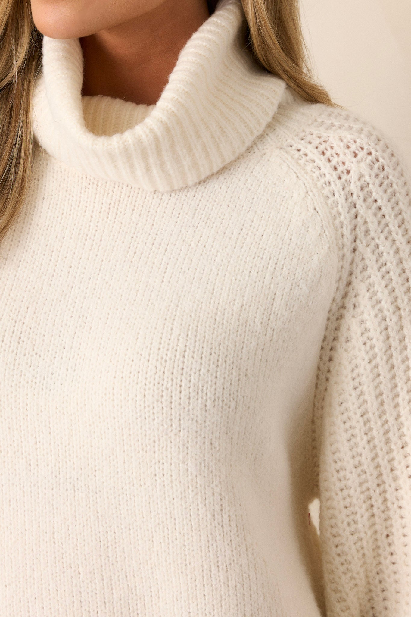 Close up view of this sweater that features a turtleneck and knit design.