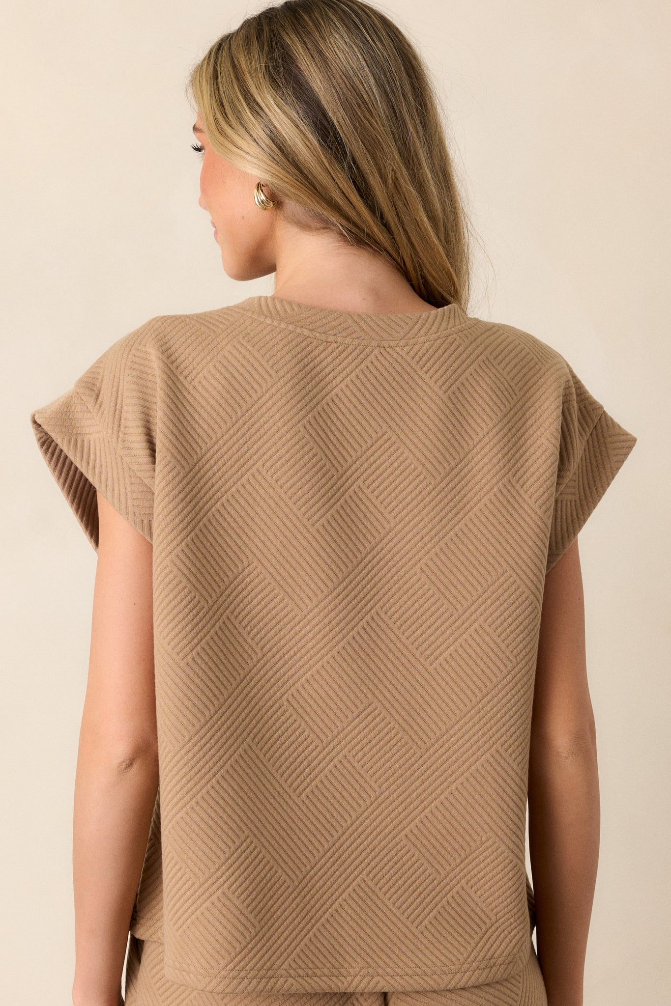 Back view of the tan top displaying the crisscross texturing and wide cuffed short sleeves.